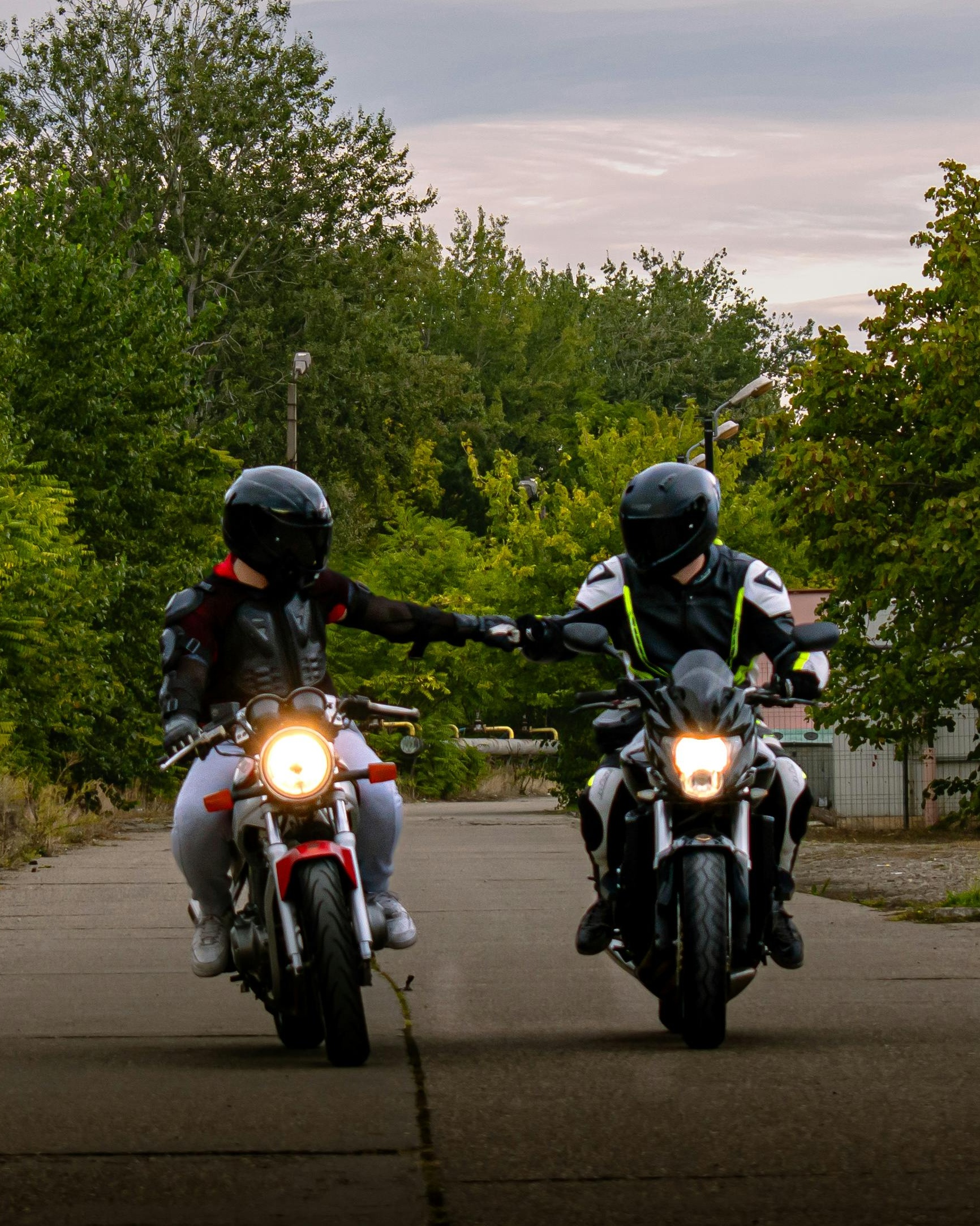 Two Motorcyclists Riding While Holding Hands