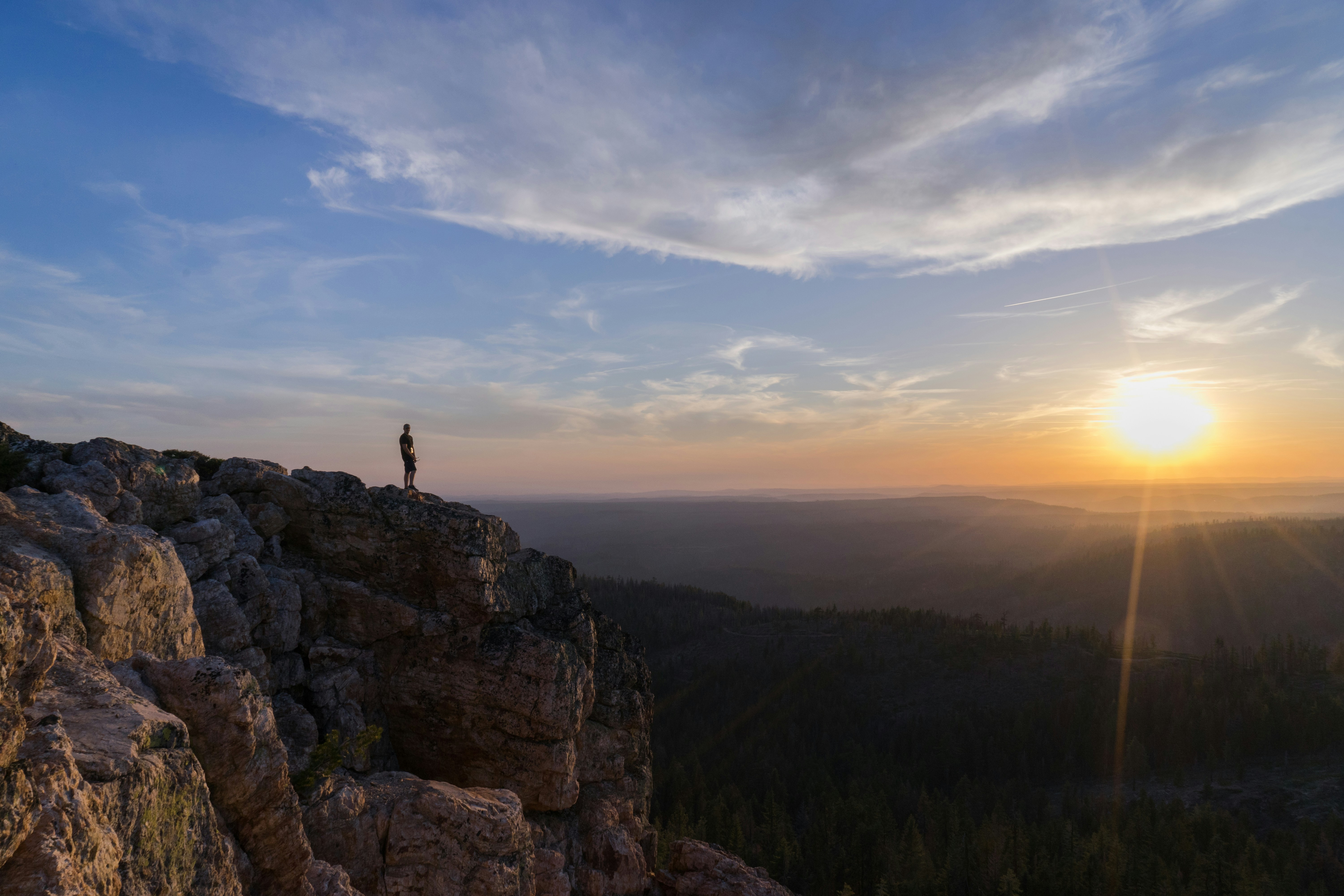 Person Standing on Cliff at Sunset