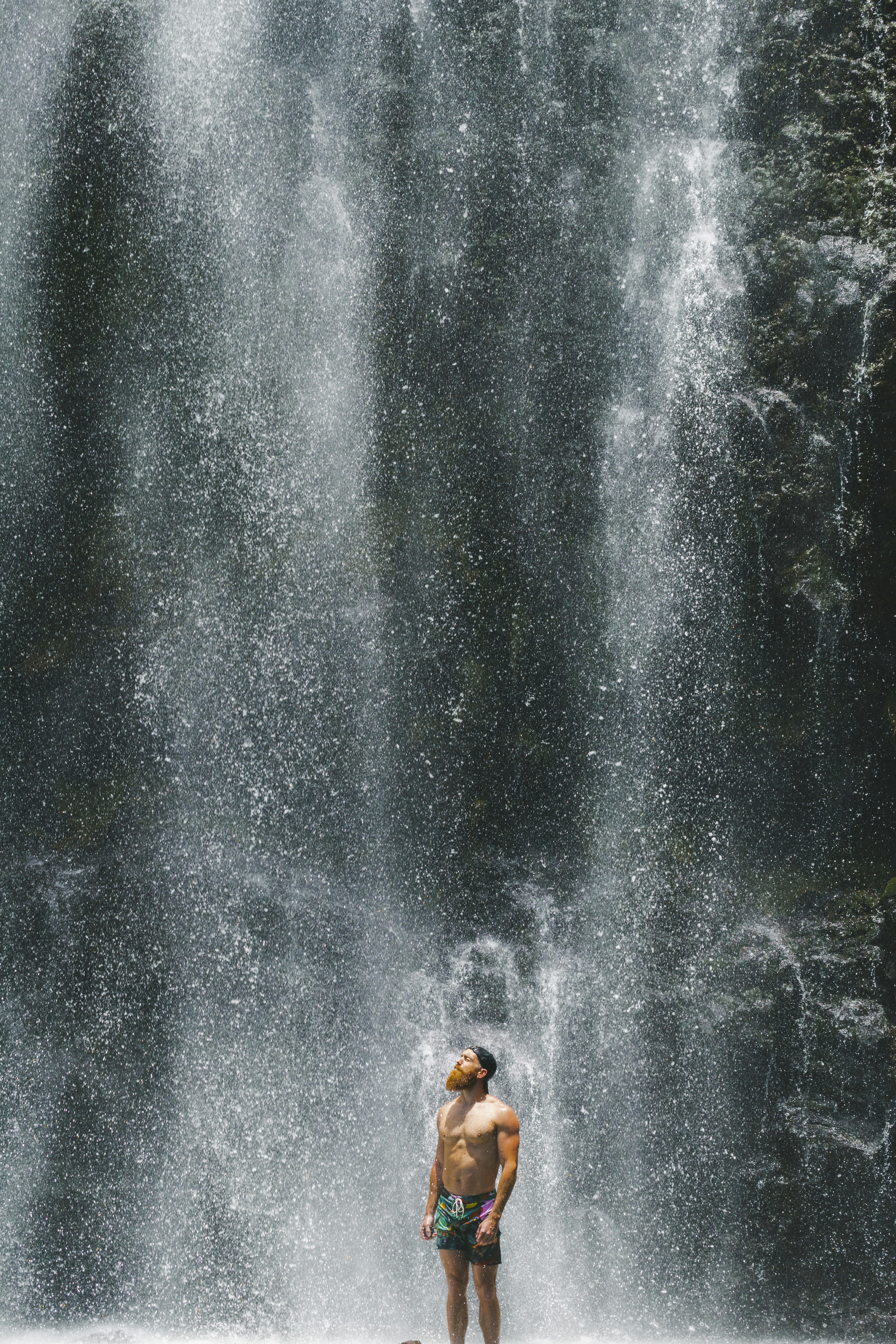 Man Standing Under Waterfall