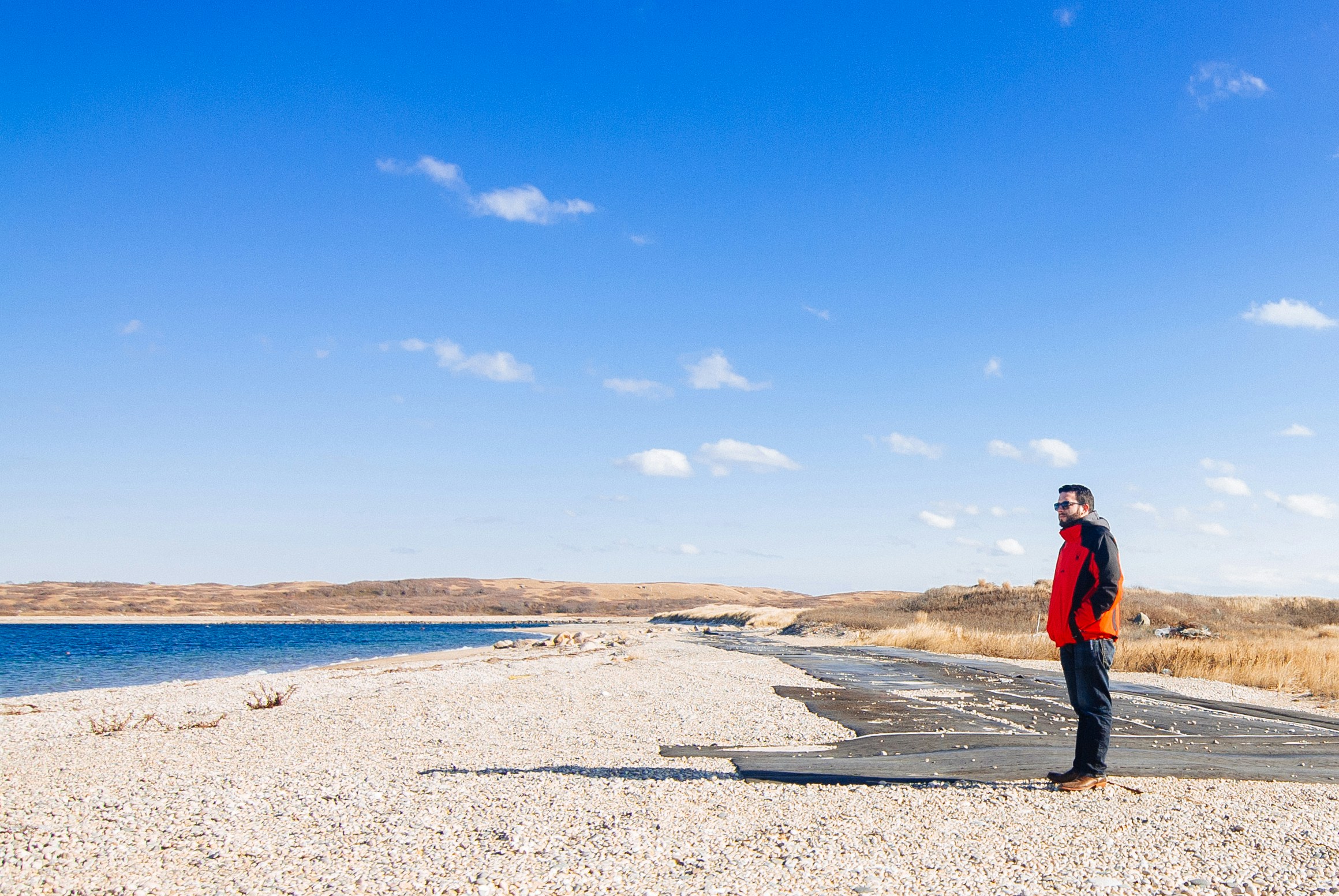 Man Standing on Coastal Gravel Beach