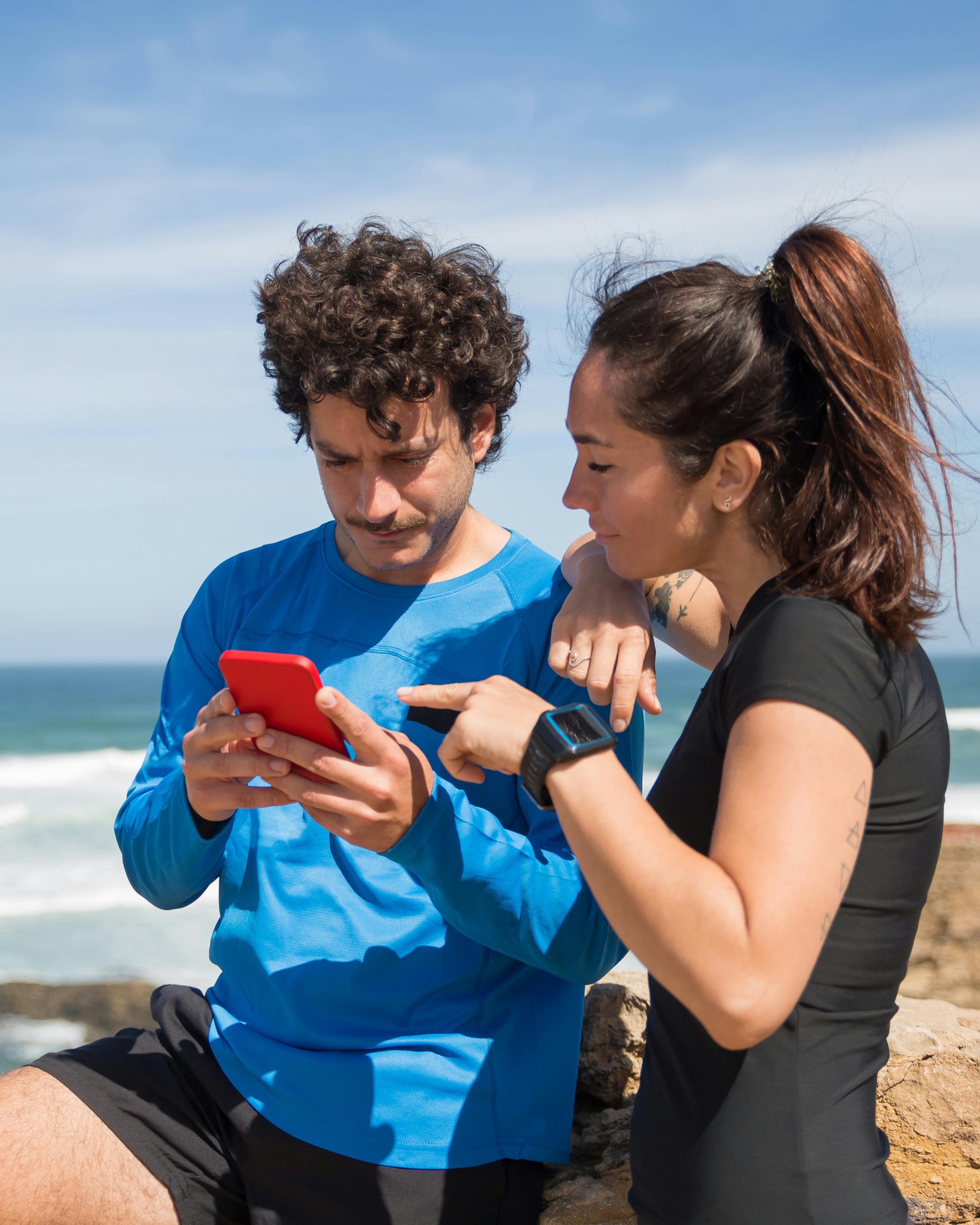 Two Runners Check Phone By Seaside