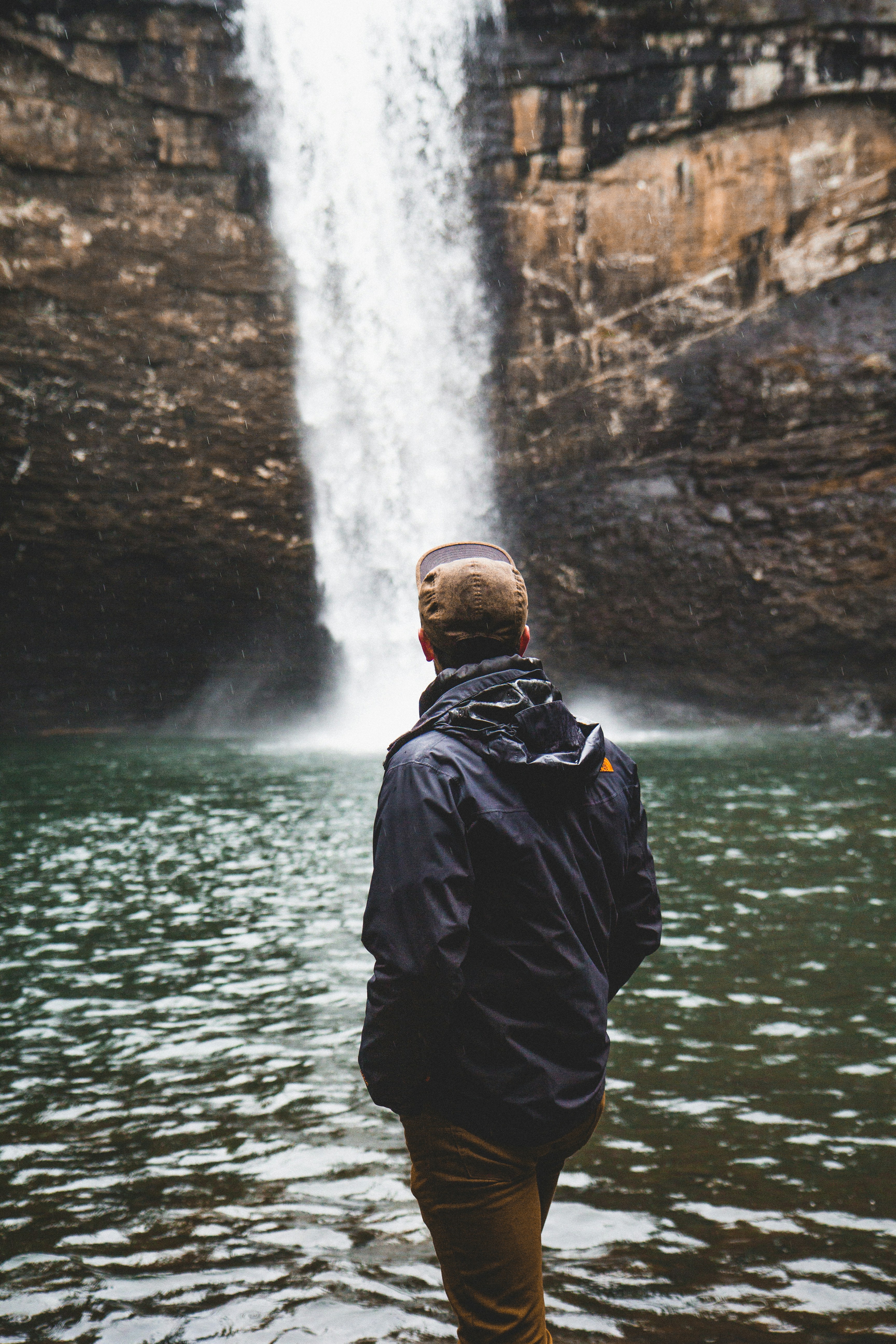Man Facing Waterfall in Pool