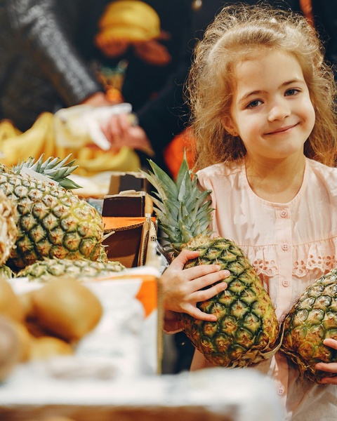 Little Girl Holding Fresh Pineapples