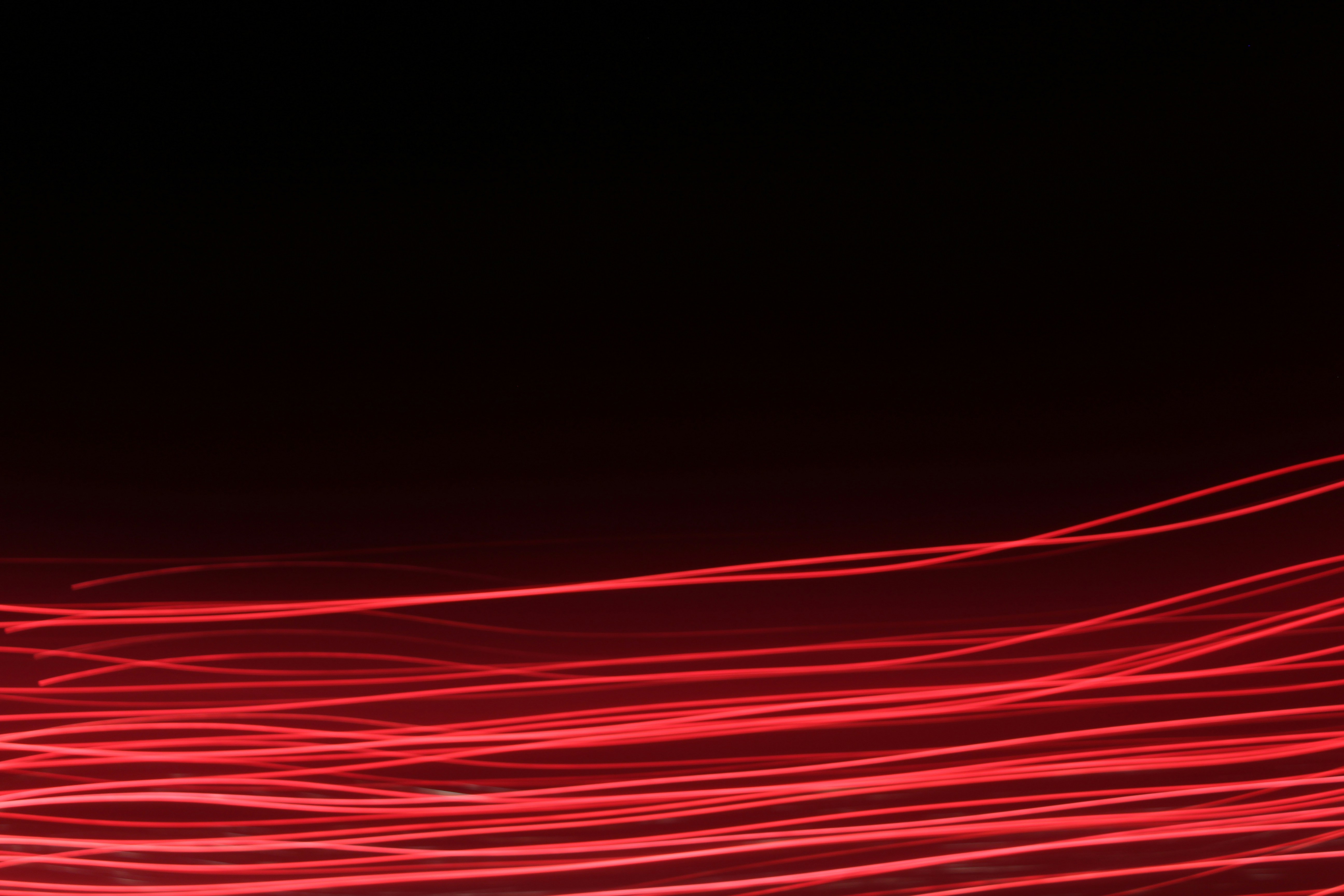 Red Wavy Light Trails on Black Background — Abstract Backgrounds