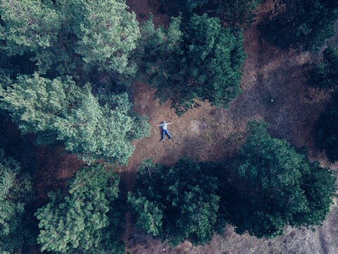 Aerial View of Man Lying in Forest Clearing