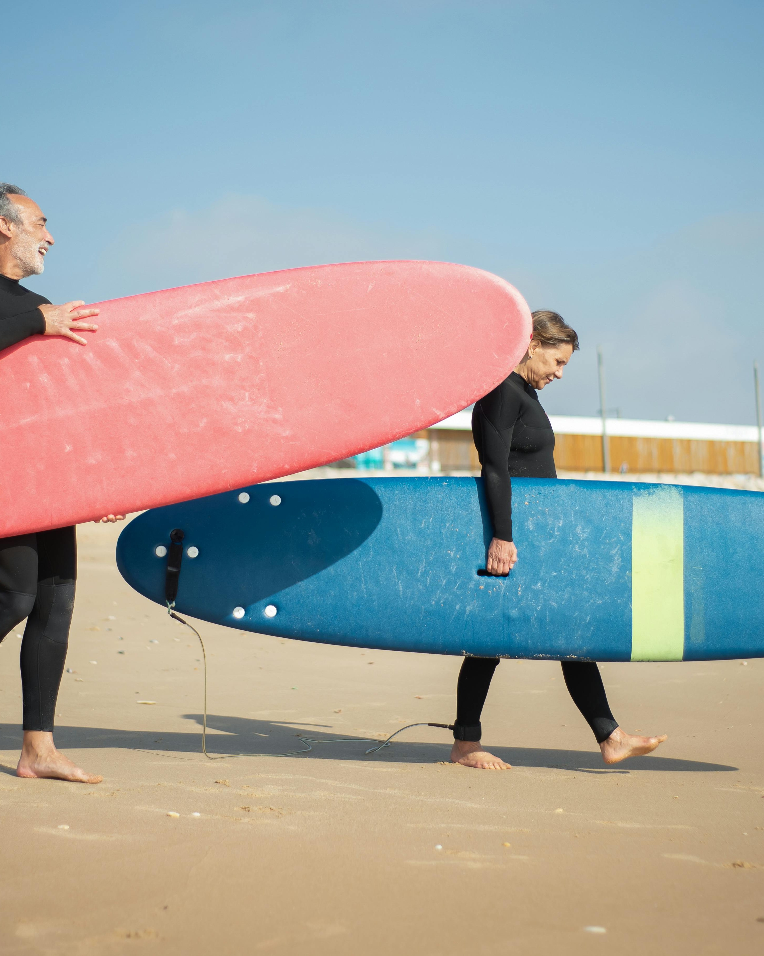 Two Surfers Carrying Boards on Beach