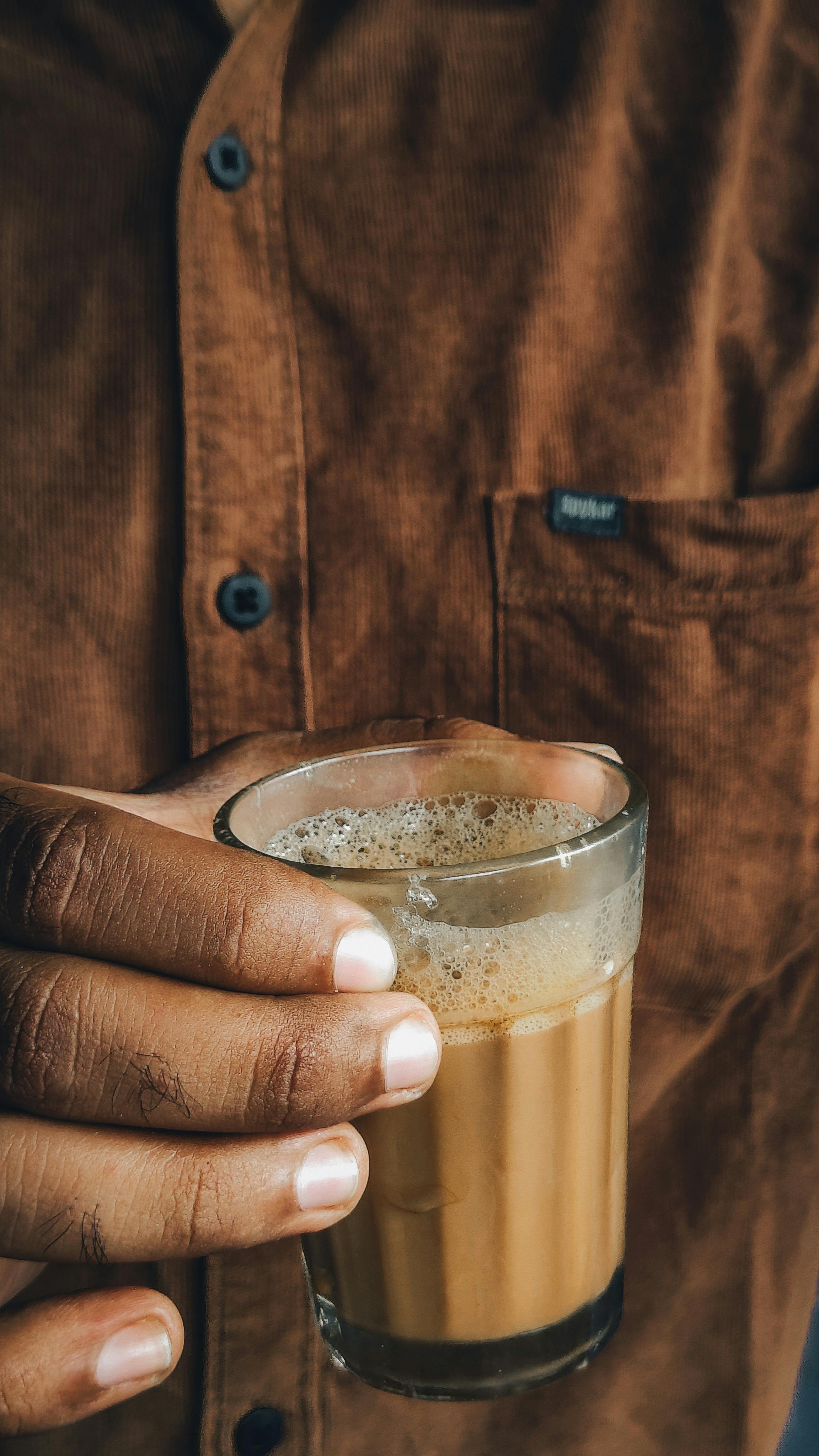 Person Holding Glass of Frothy Chai