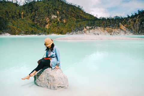 Woman Sitting by Turquoise Lake