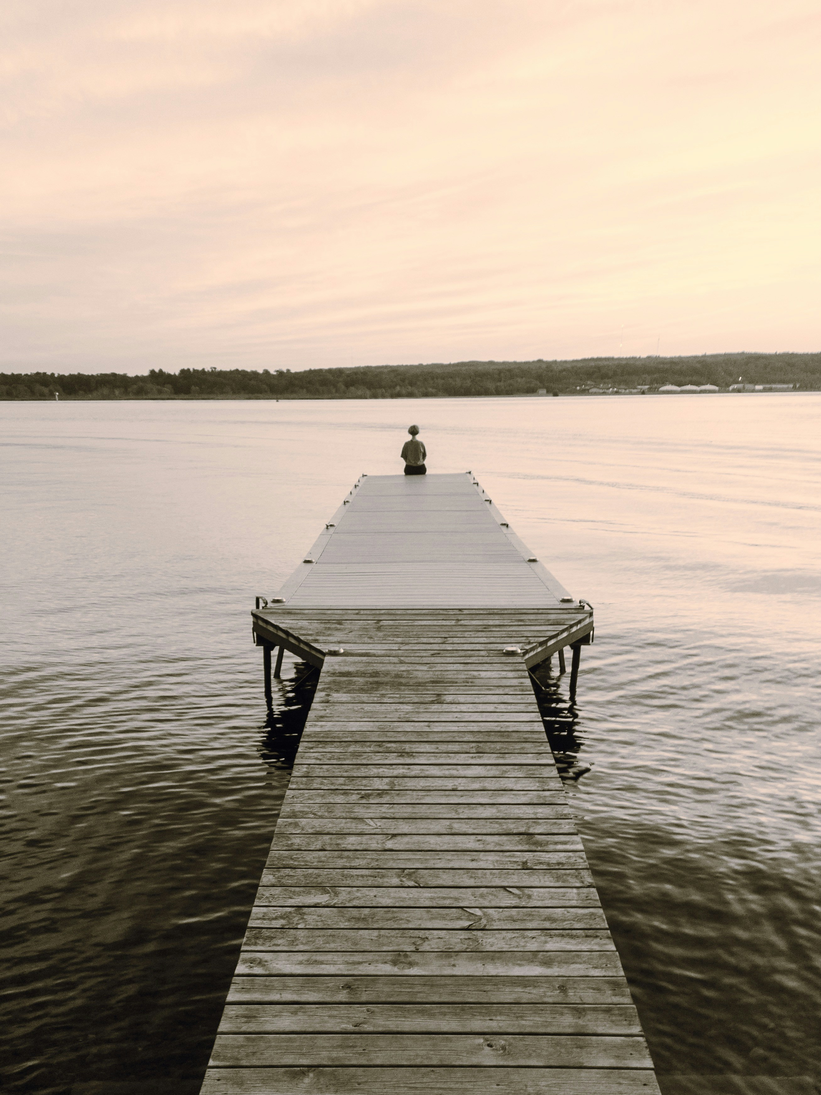 Person Sitting On Lake Dock At Dusk