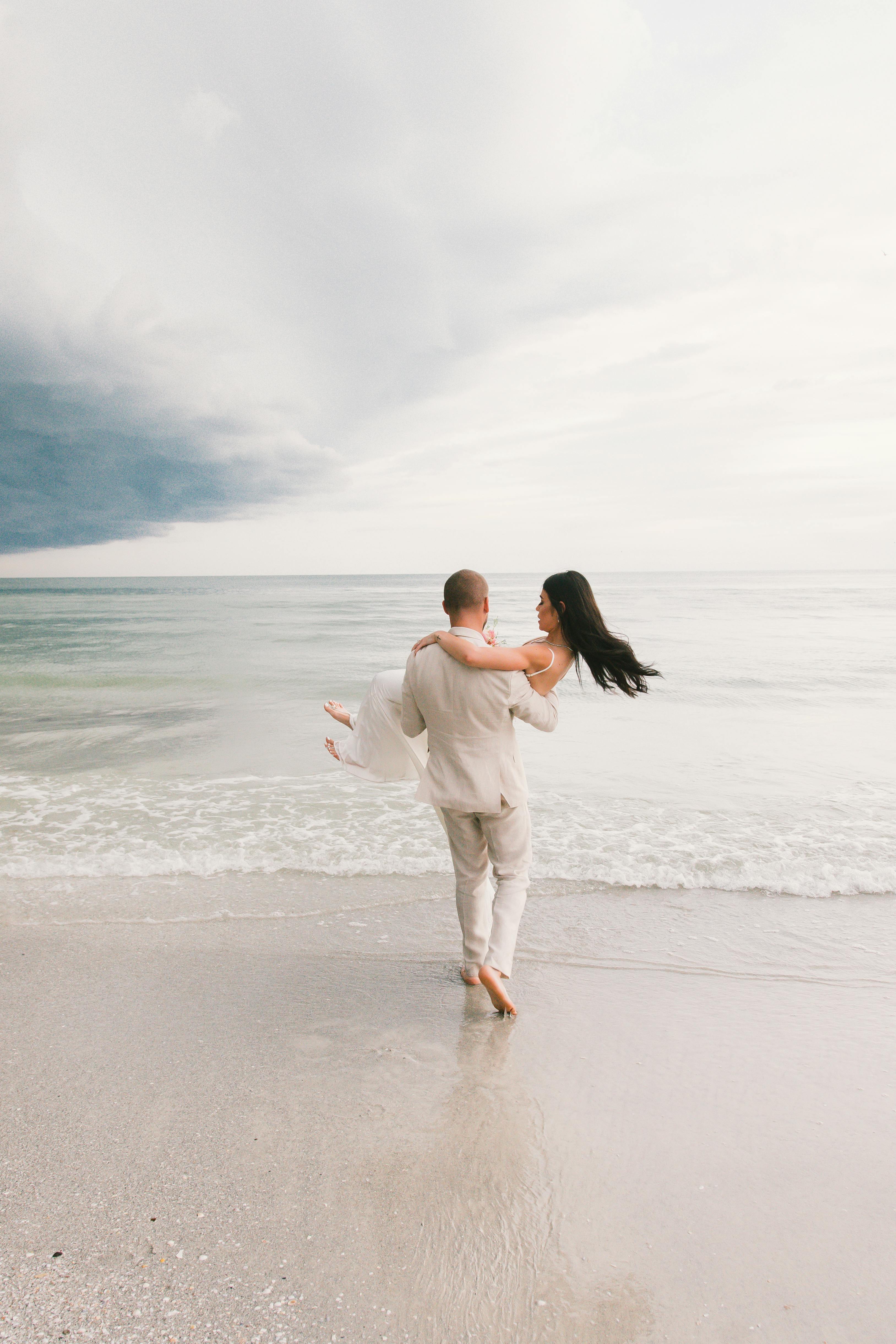 Groom Carrying Bride on Beach