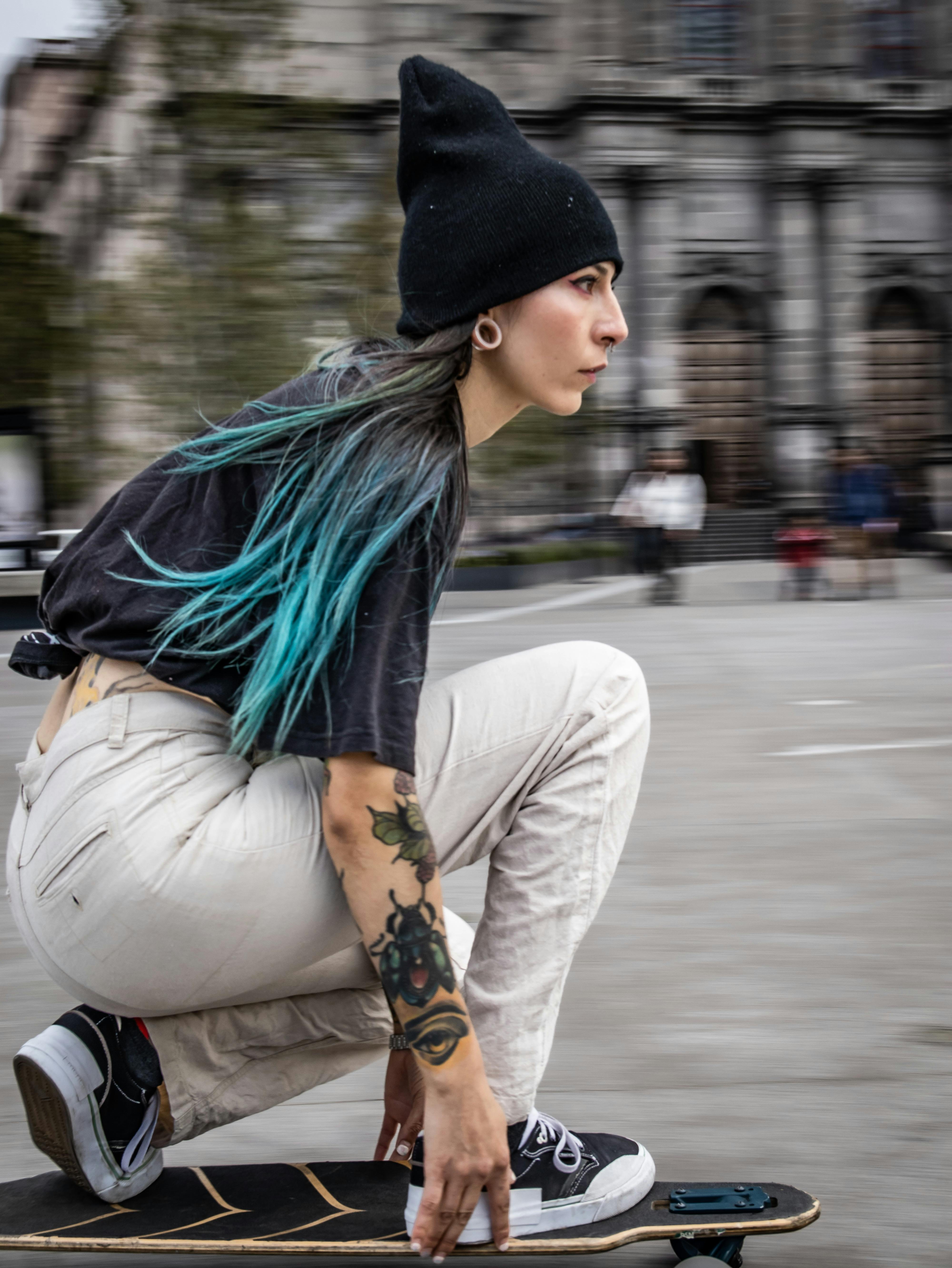 Tattooed Woman Longboarding in City Square