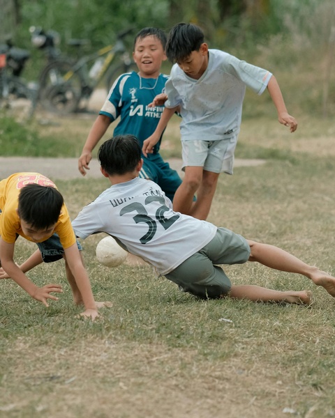 Four Boys Playing Soccer On Grass