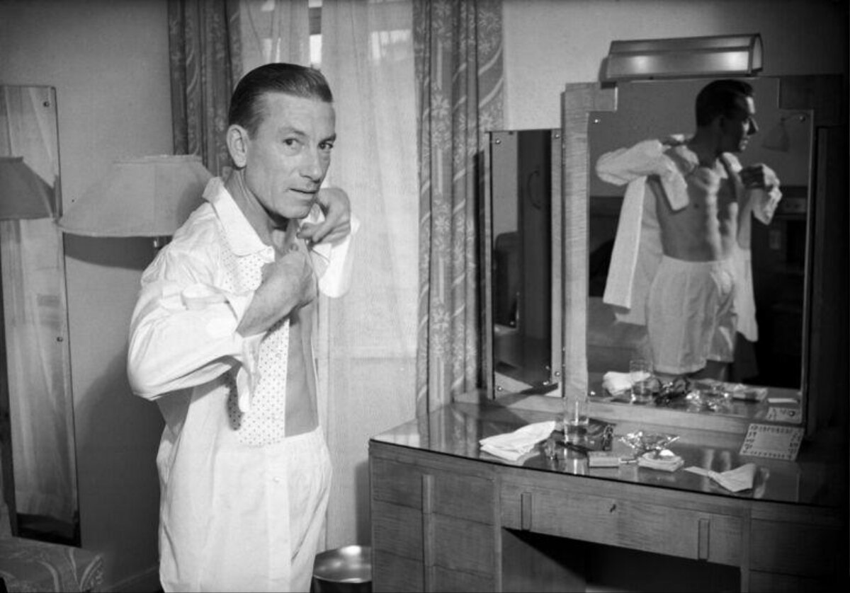 Man Putting On Shirt Before Mirror