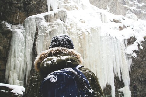Hiker Facing Frozen Snowy Waterfall