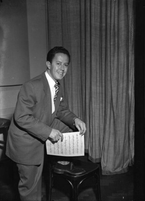 Smiling Man Holding Sheet Music