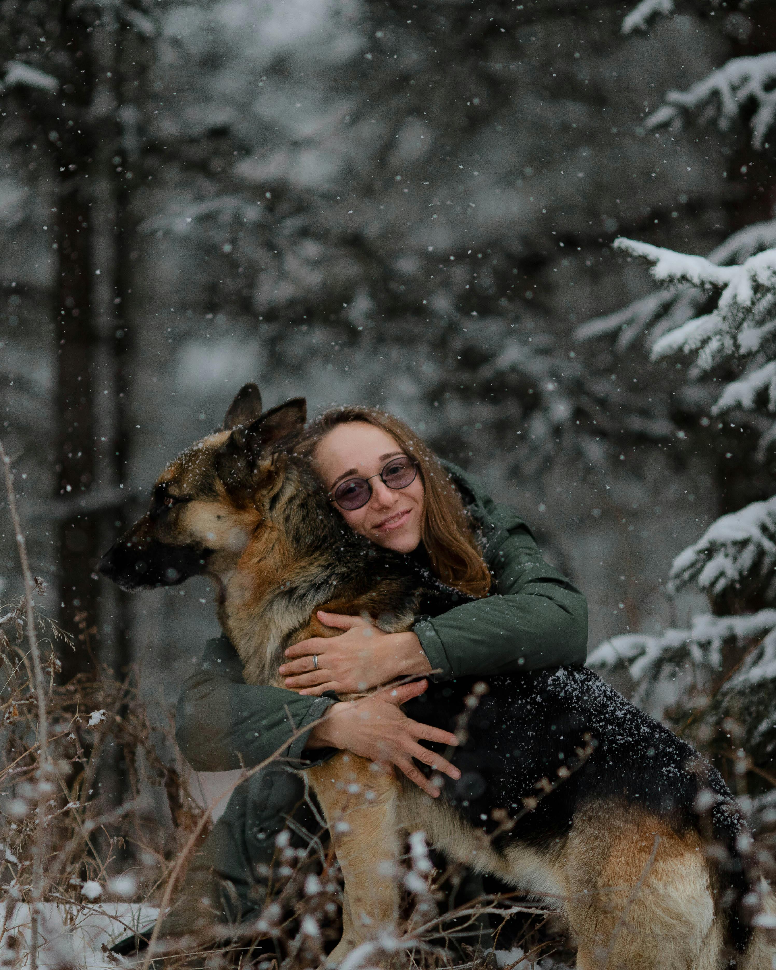 Woman Hugging German Shepherd in Snowy Forest