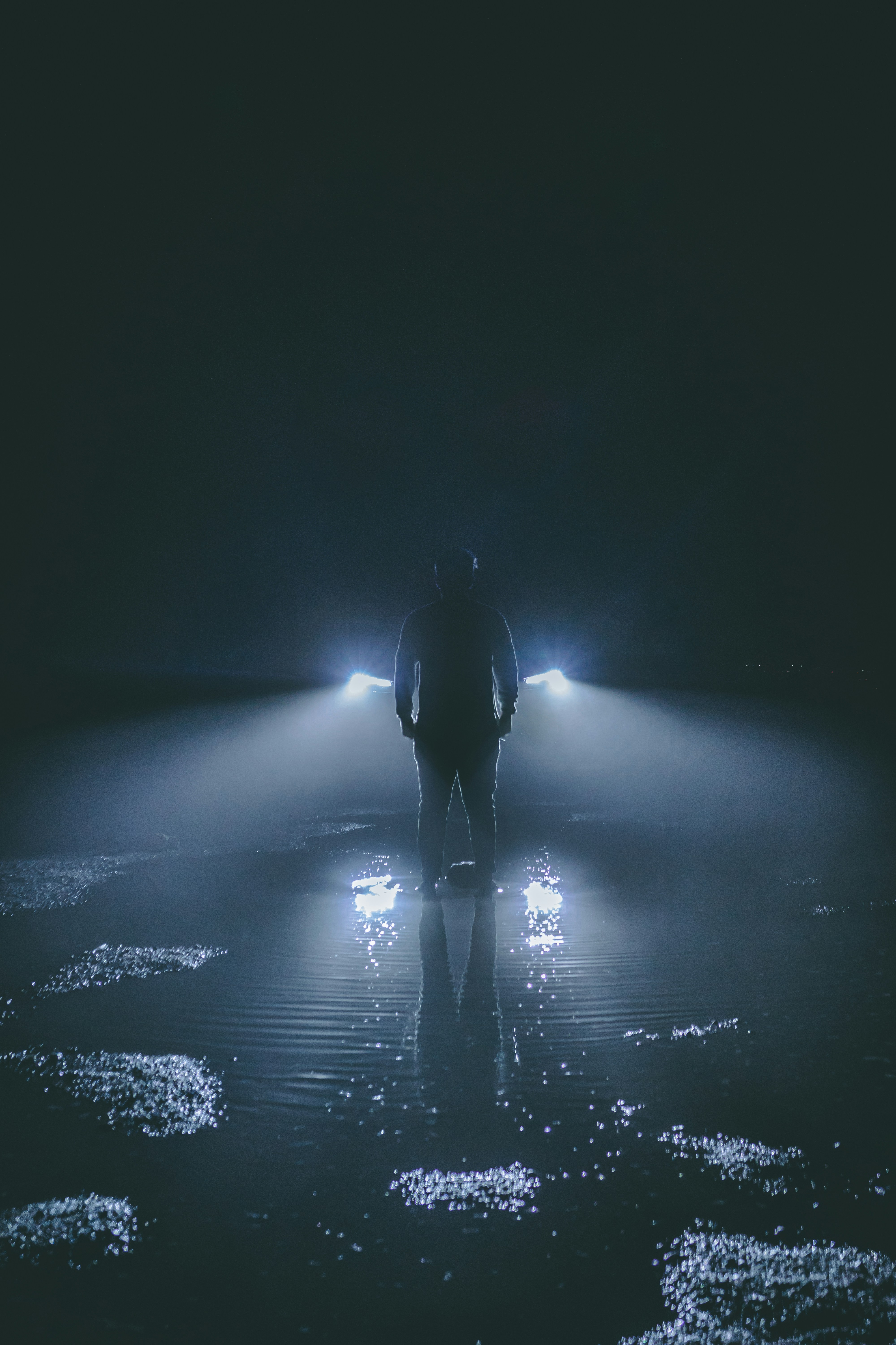 Man's Silhouette Against Night Headlights