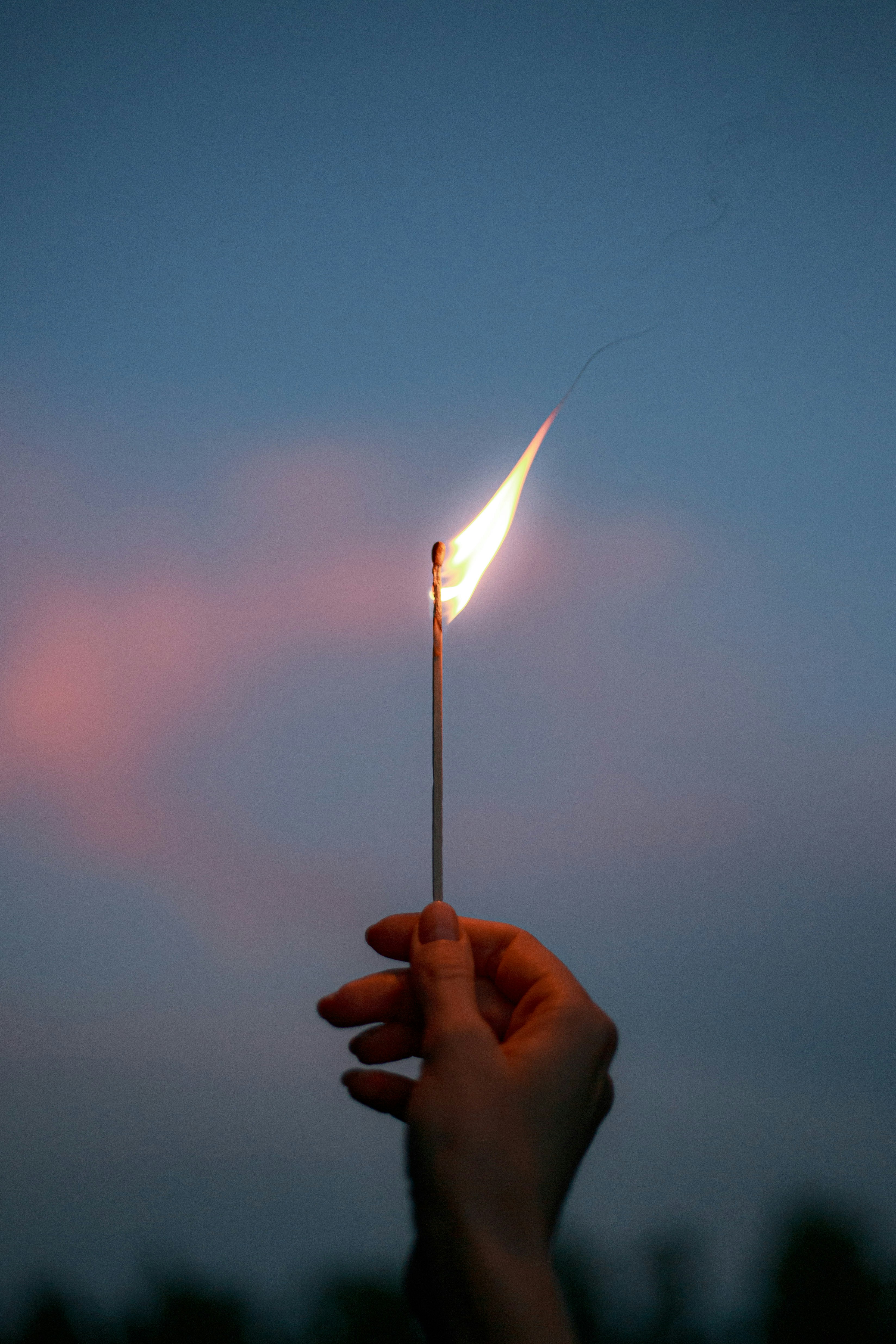 Hand Holding Burning Match At Dusk