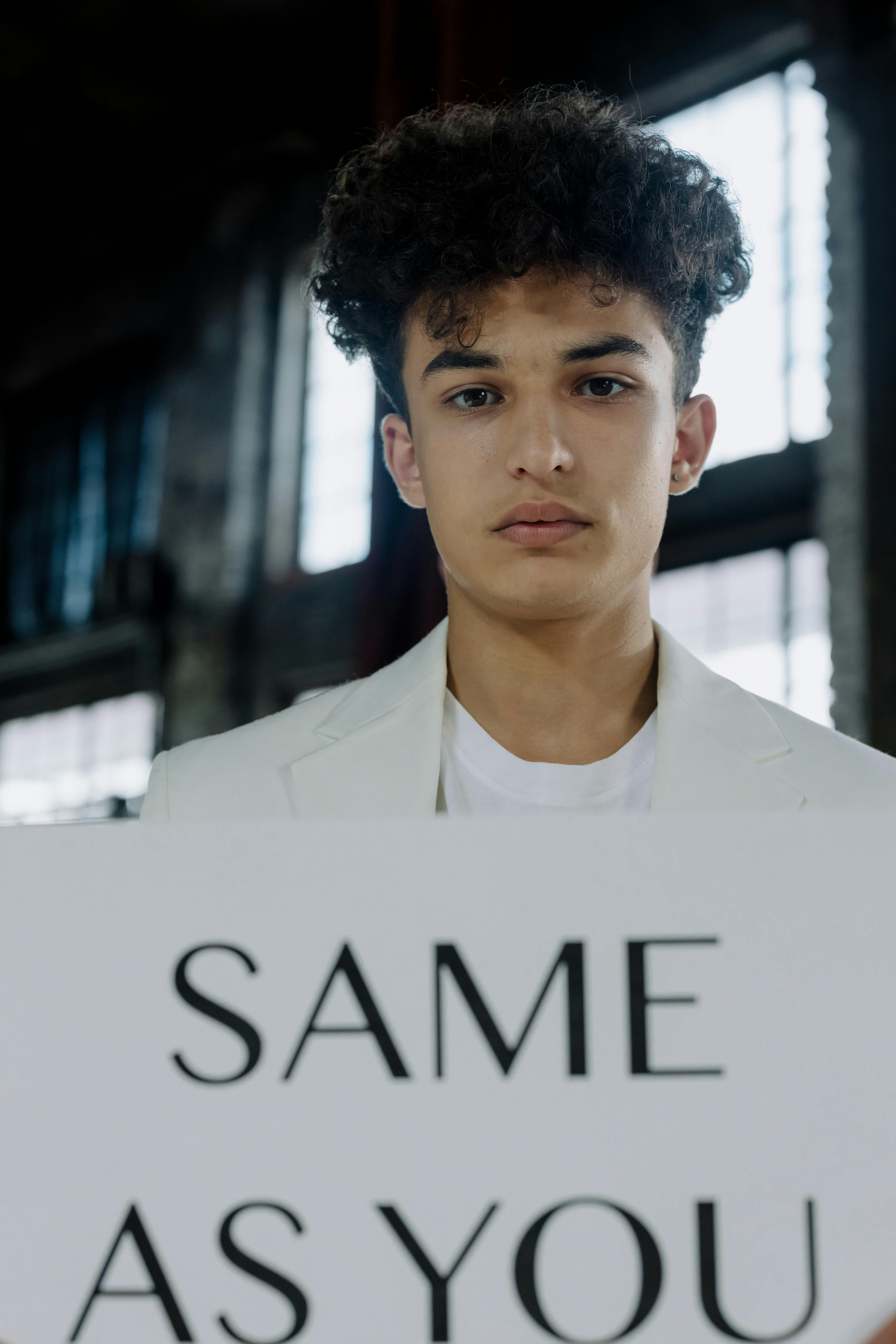 Young Man Holding Same As You Sign