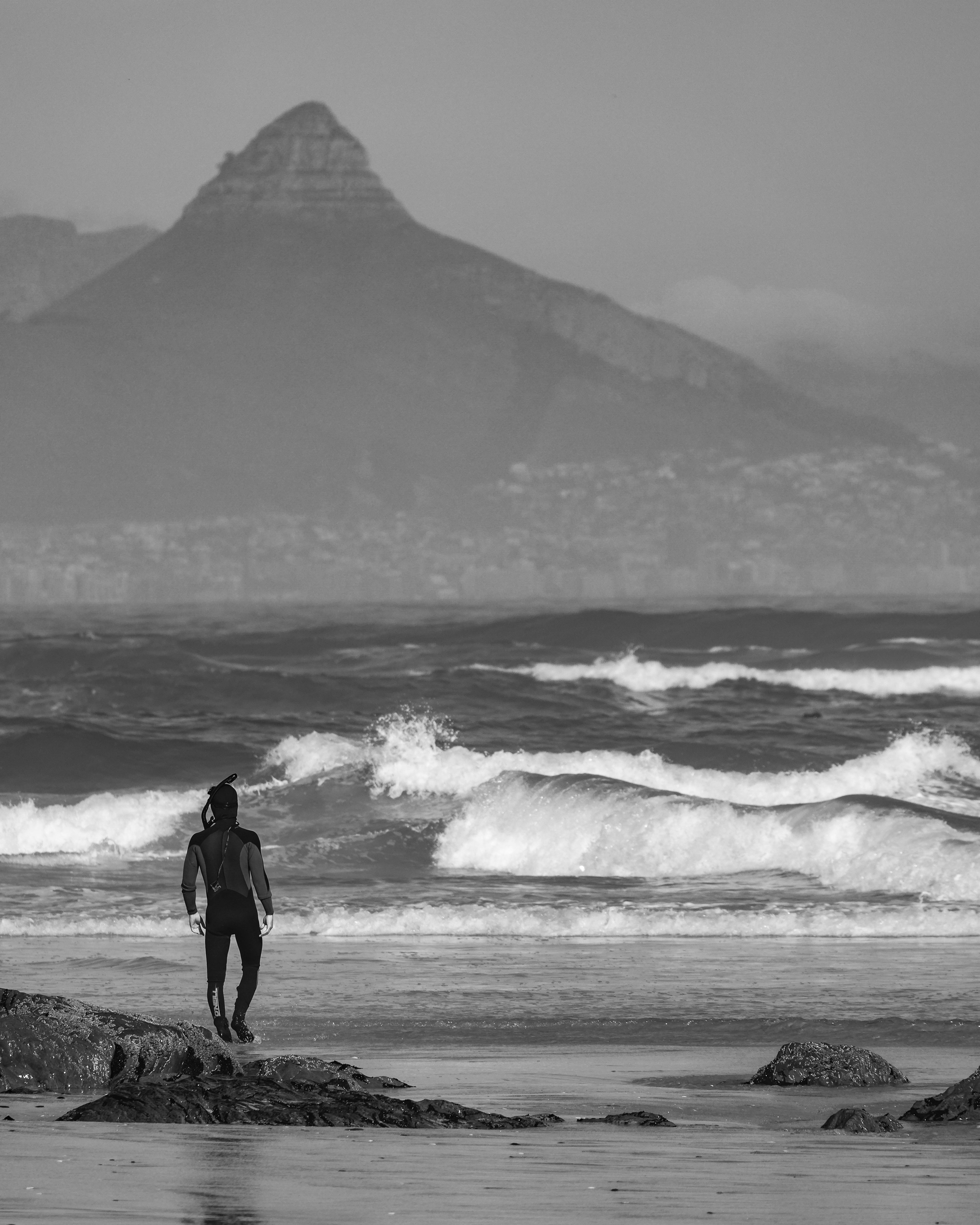 Freediver Entering Ocean with Distant Mountain View