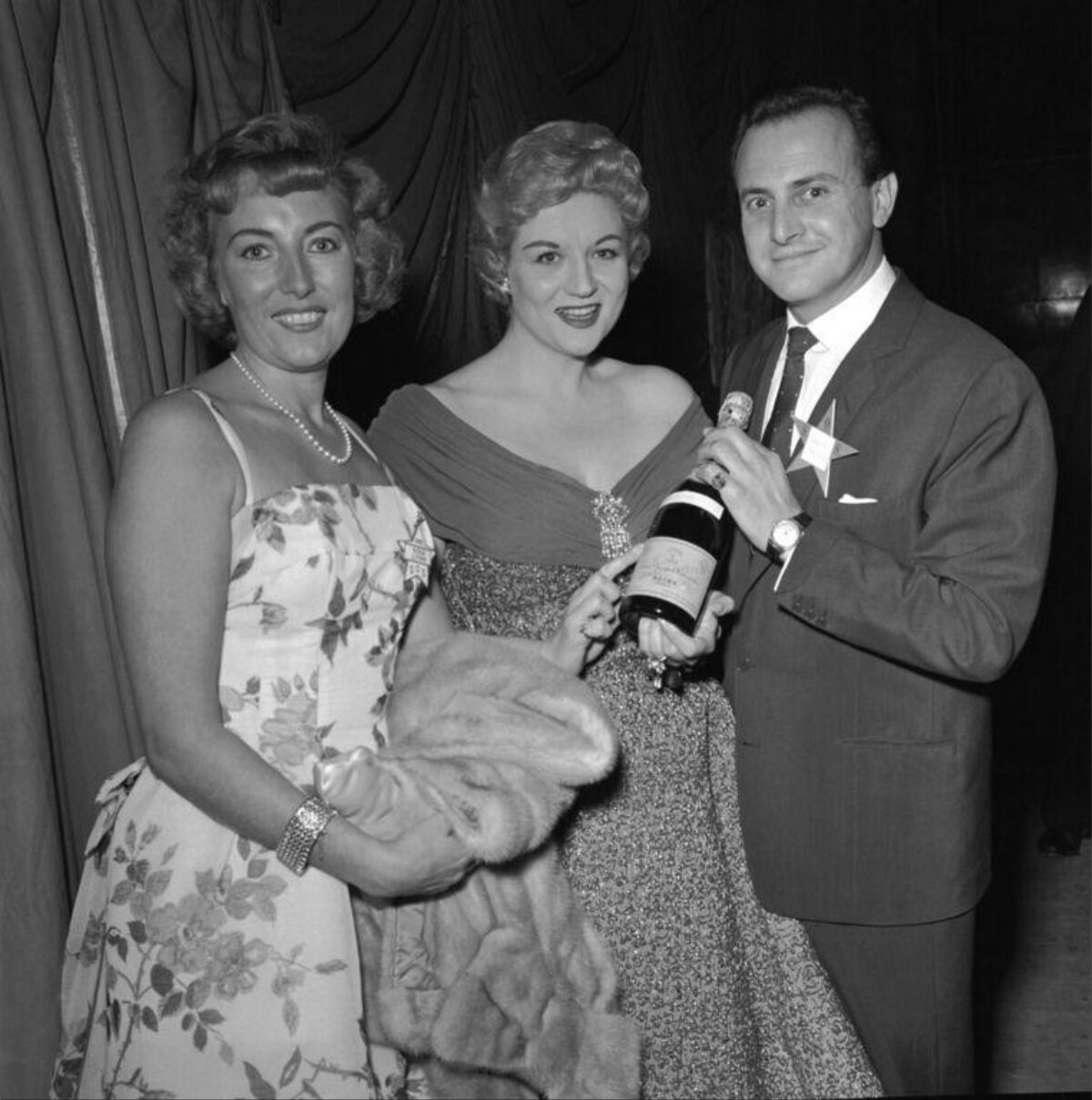 Three People Posing With Champagne at Formal Event