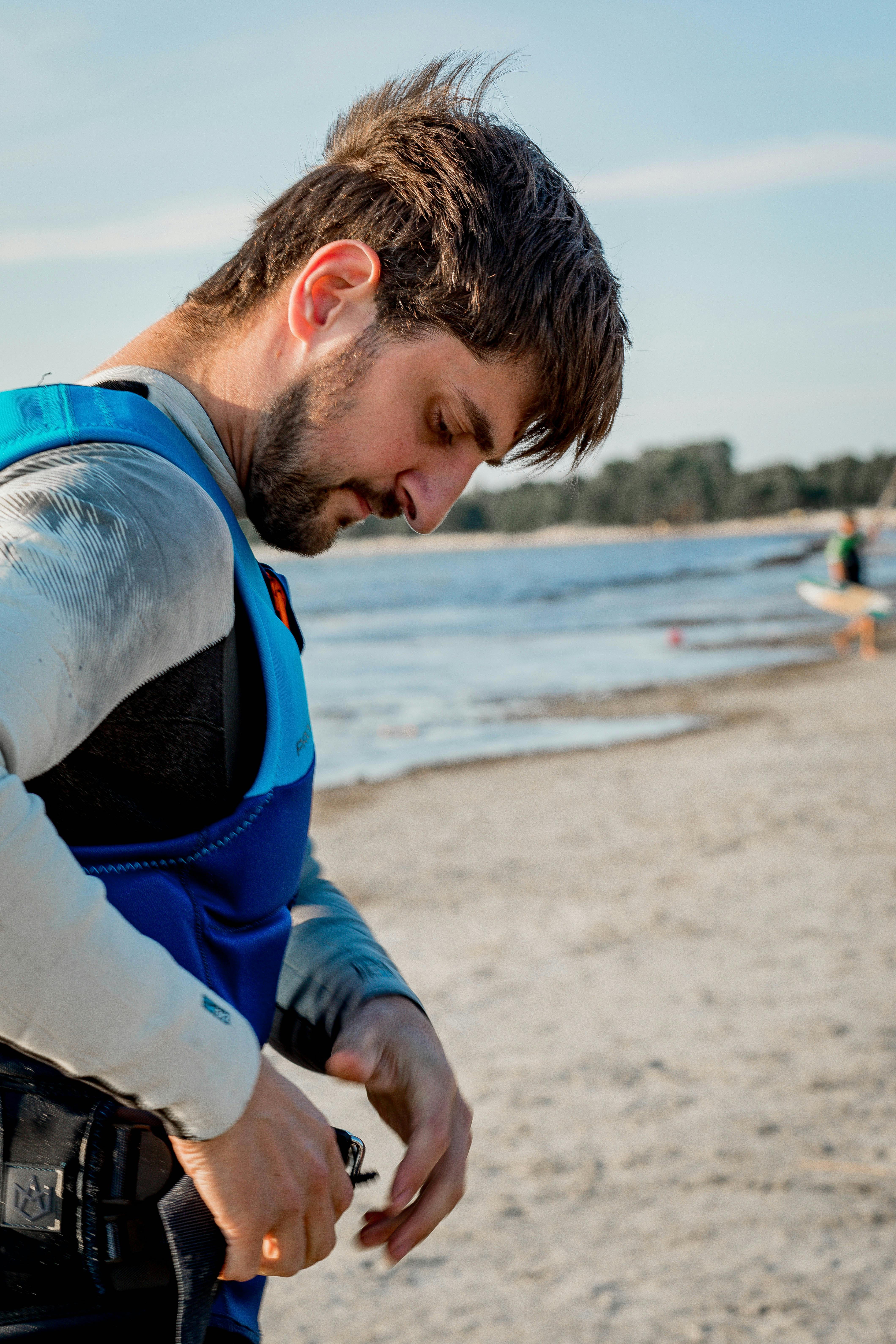 Man Adjusting Gear on Sandy Beach