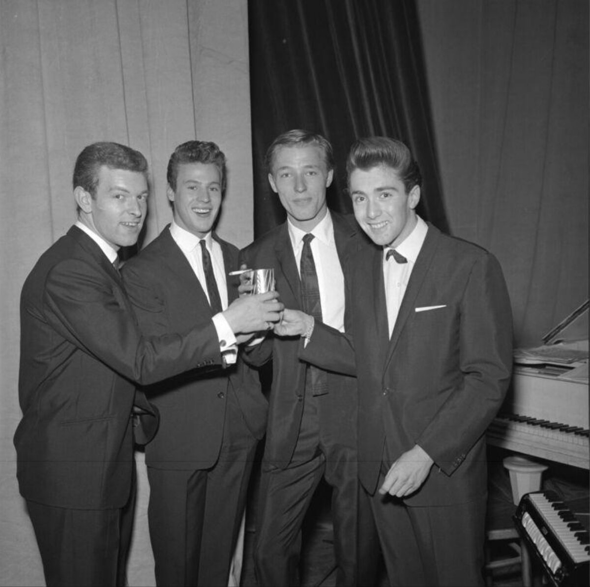 Four Young Men In Suits Toasting