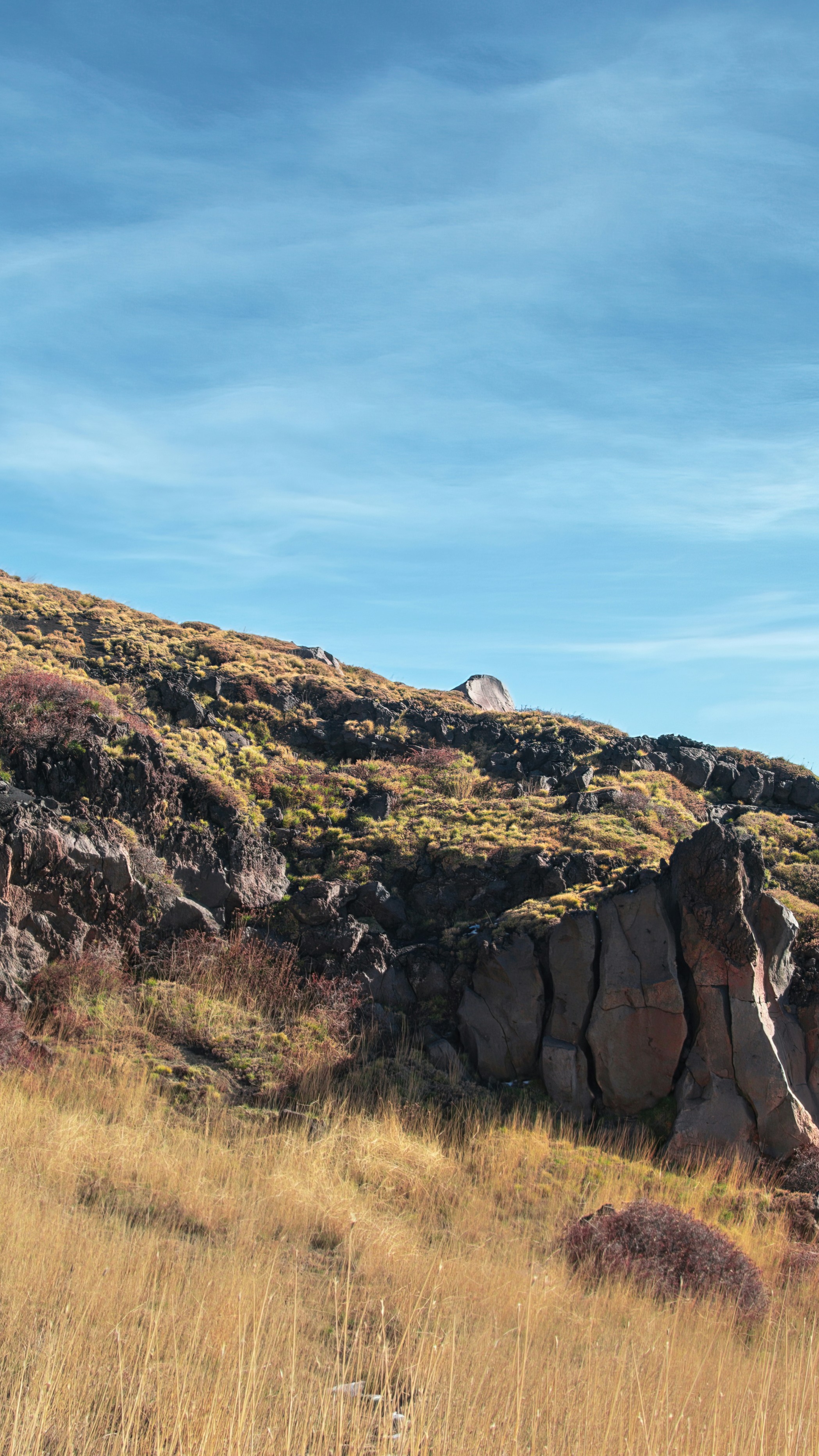 Rocky Grassy Hillside Under Blue Sky