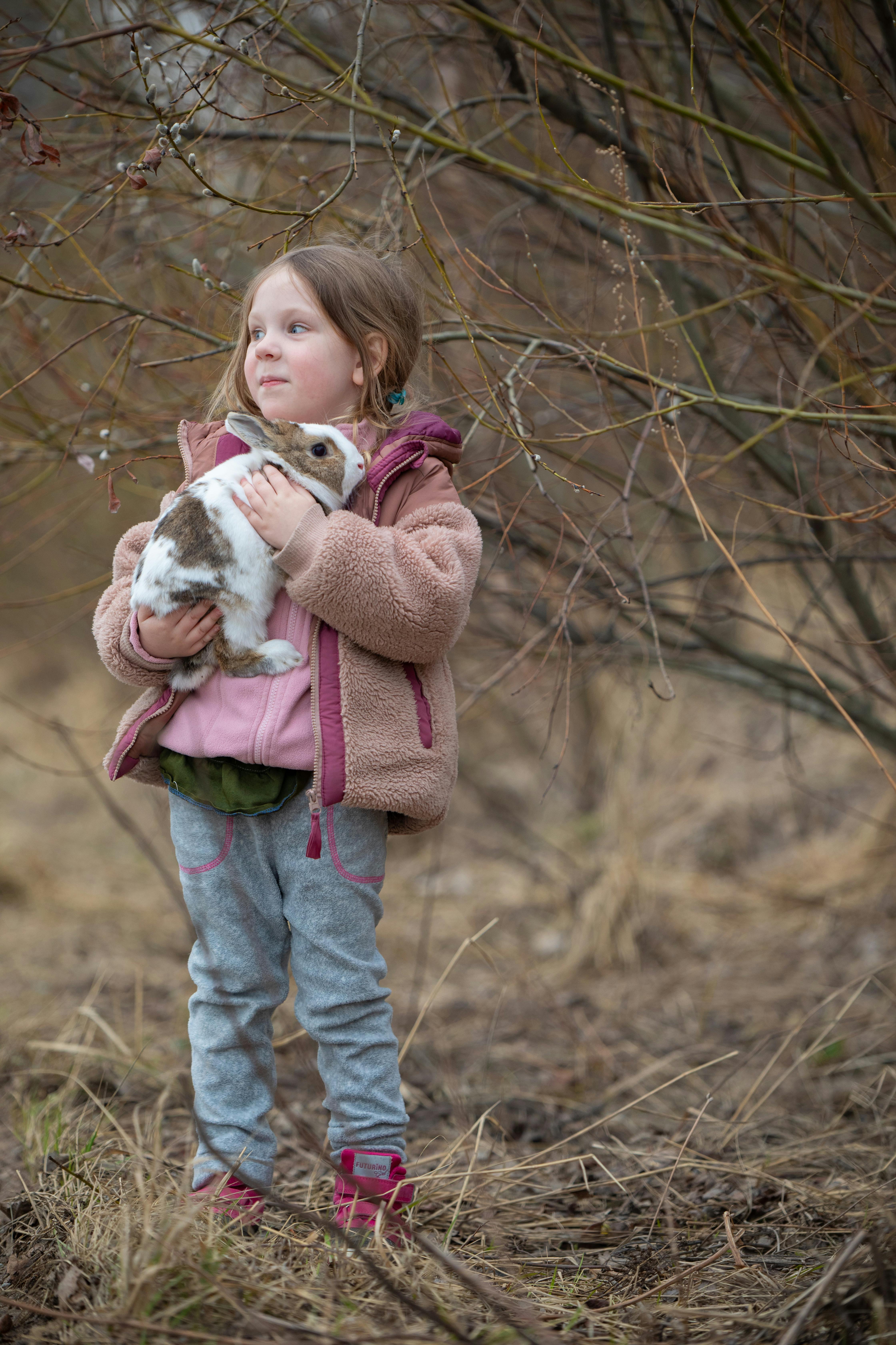 Little Girl Holding Pet Rabbit Outdoors