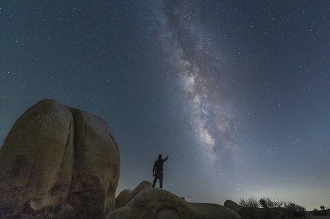 Person Reaching For Milky Way Over Desert Rocks
