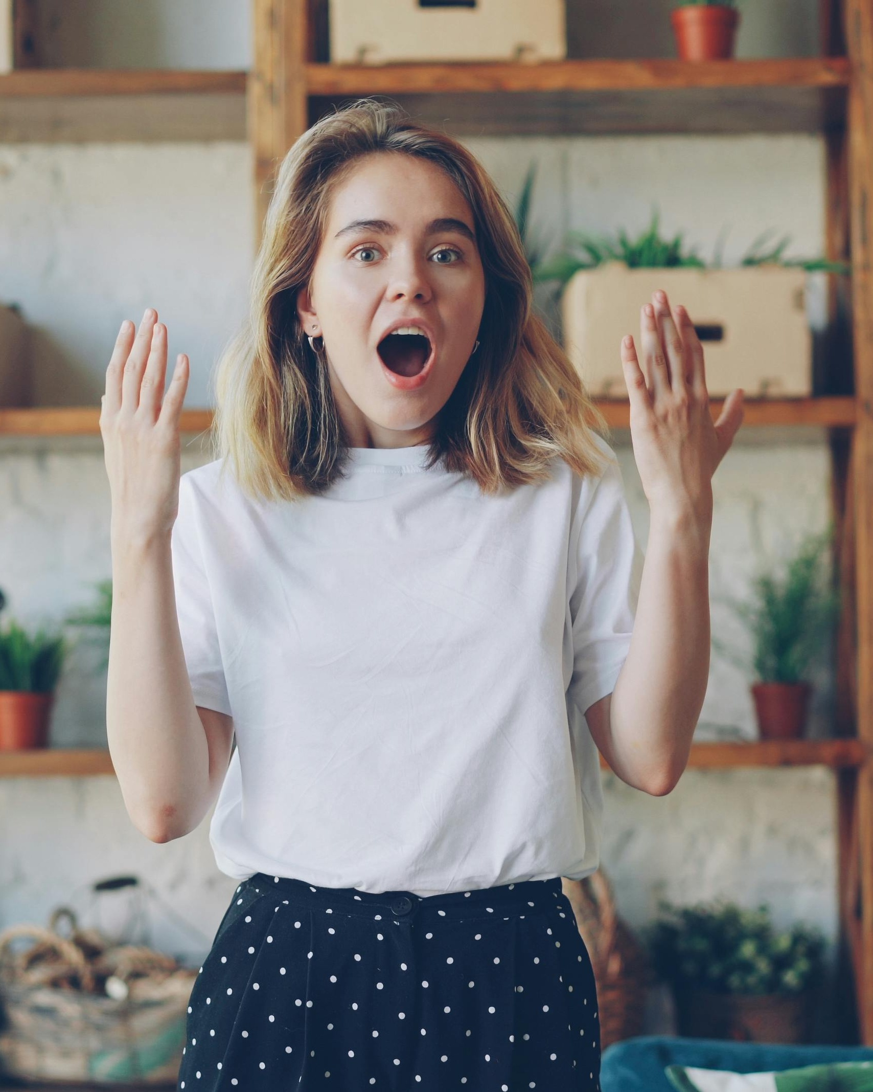 Surprised Young Woman With Raised Hands