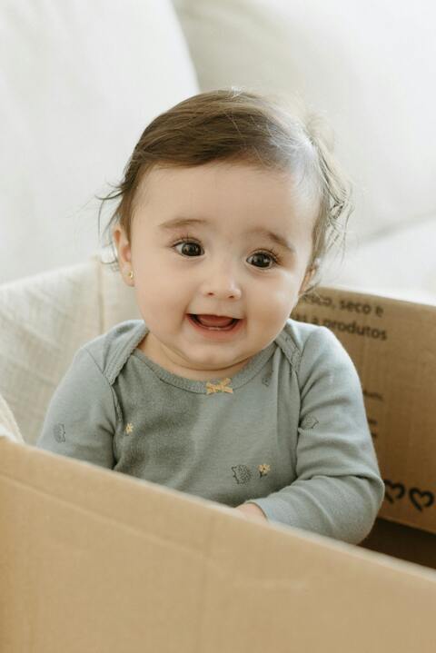 Smiling Baby Sitting In Cardboard Box
