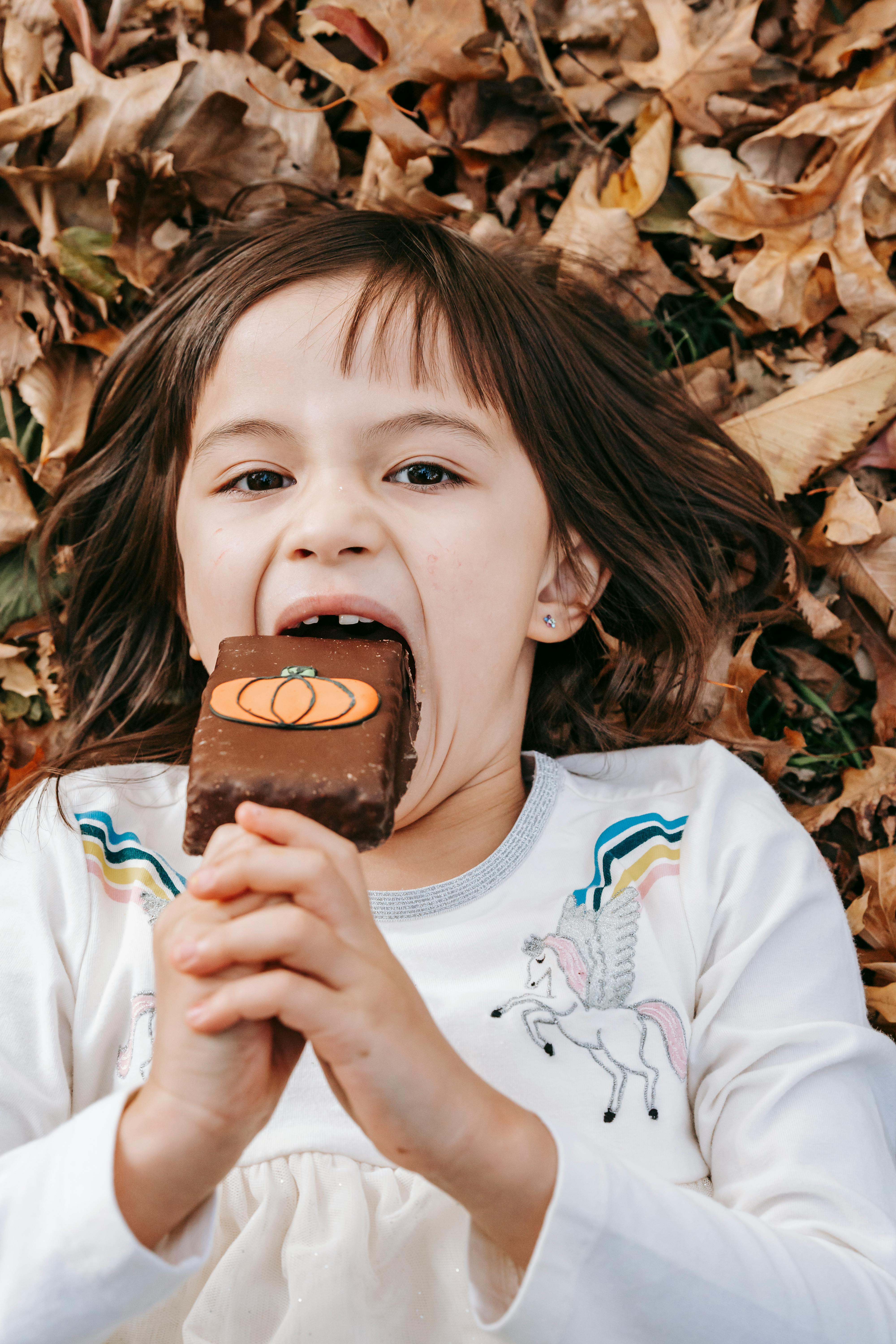 Girl Eating Pumpkin Treat On Fall Leaves