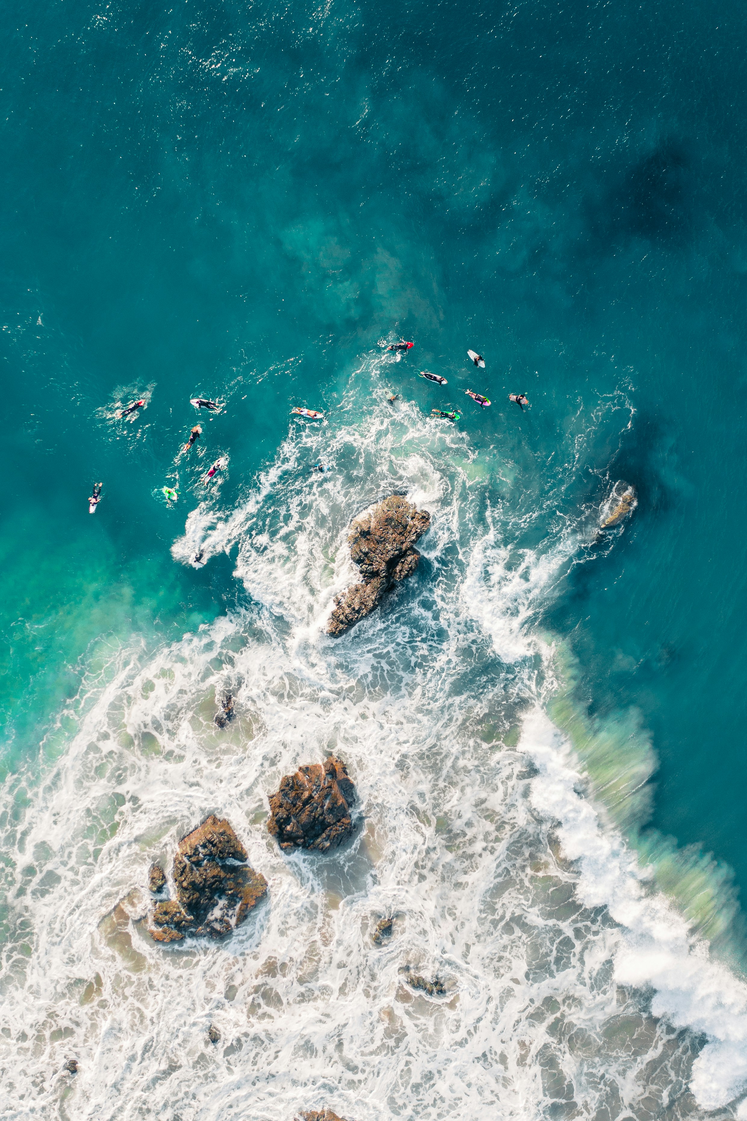 Aerial View of Surfers Near Coastal Rocks