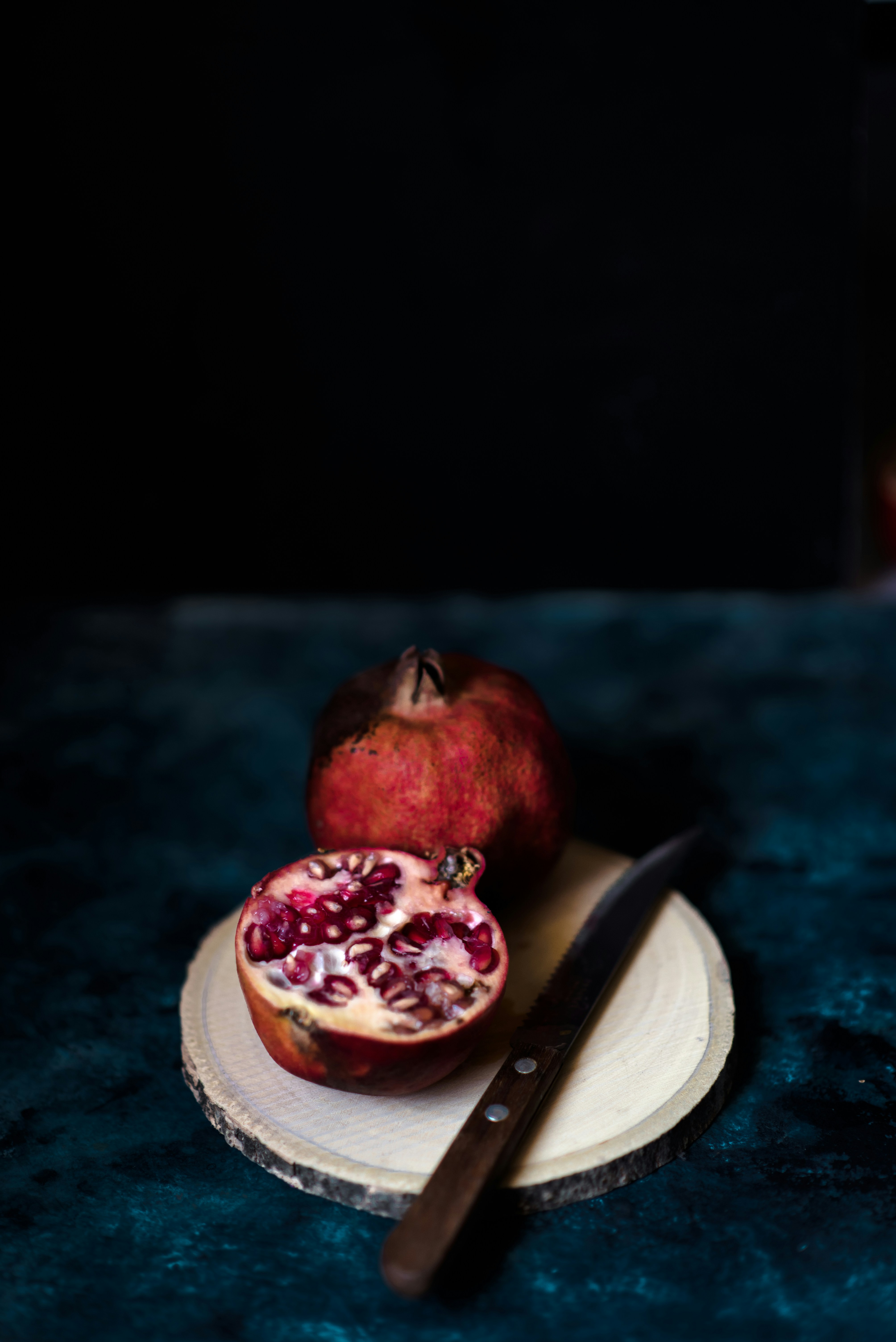 Cut and Whole Pomegranate on Wooden Board