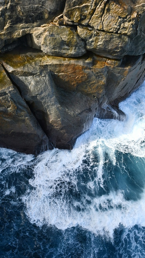 Ocean Waves Crash Against Rocky Cliff