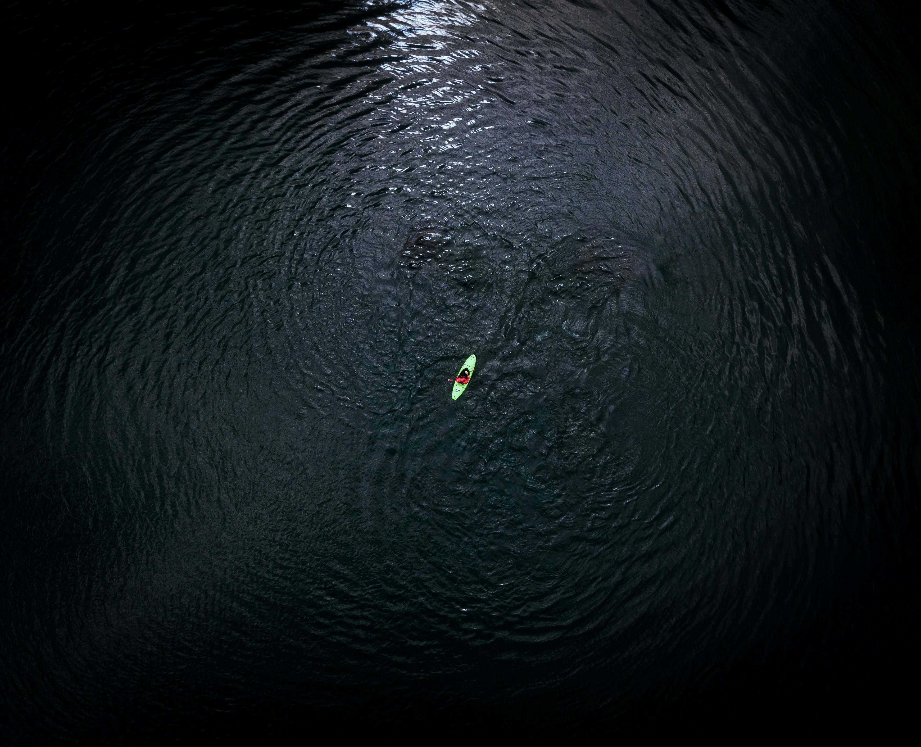 Lone Kayak on Swirling Dark Water