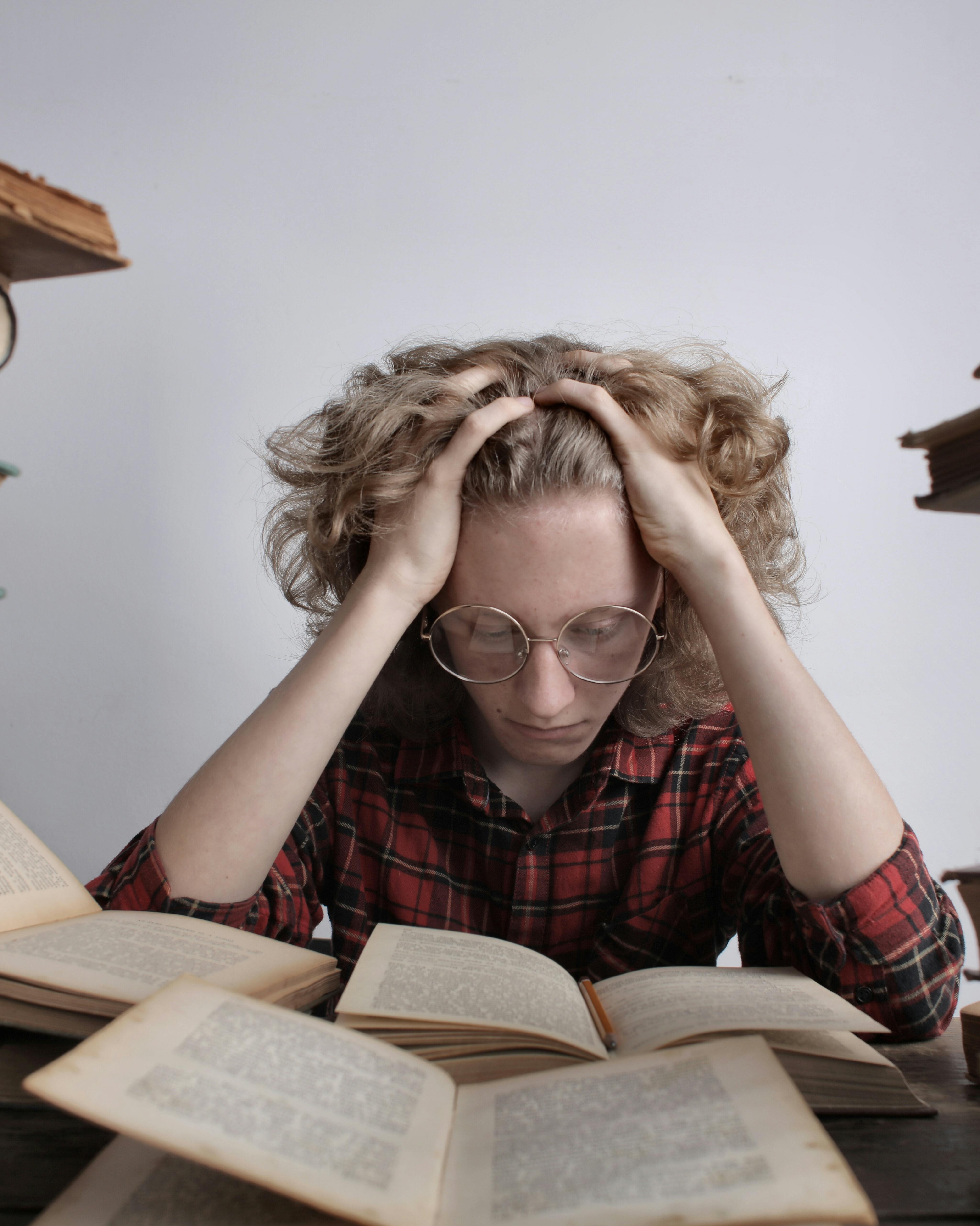 Stressed Student Studying With Many Open Books