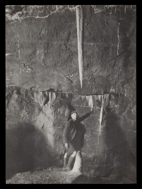 Explorer and Giant Ice Stalactite in Cave