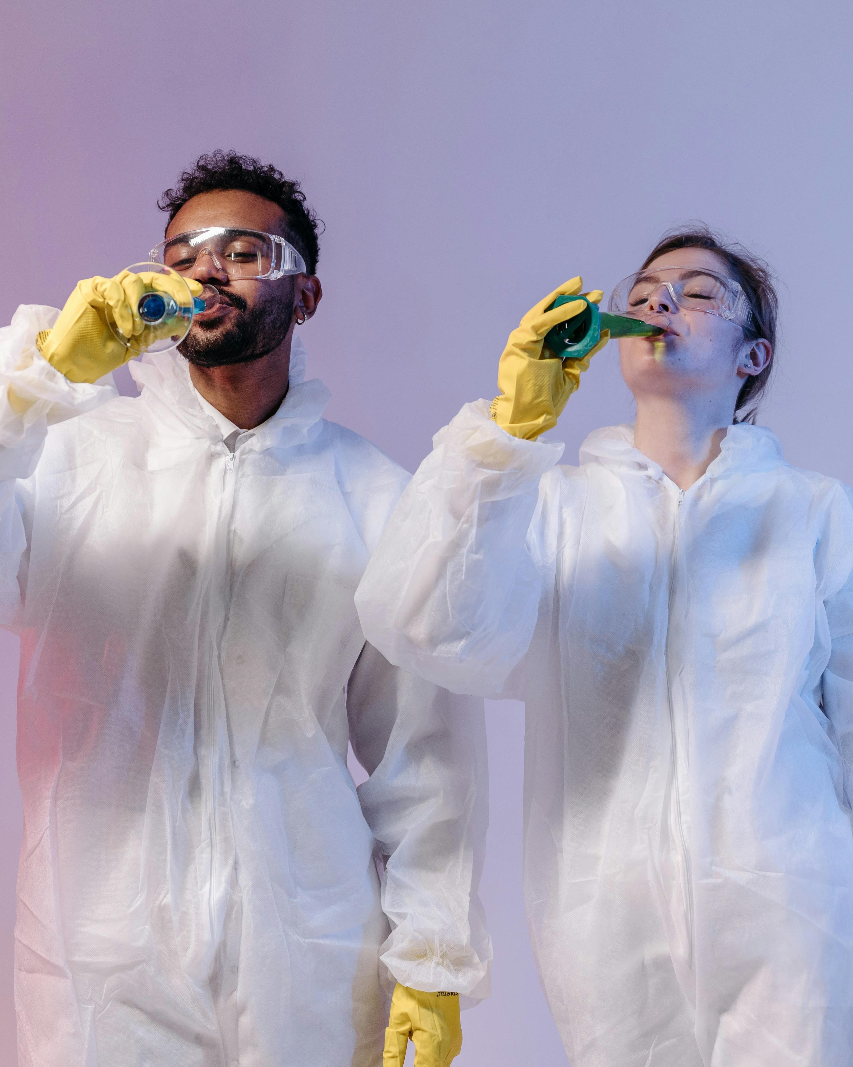 Two Hazmat Workers Drinking from Lab Glassware