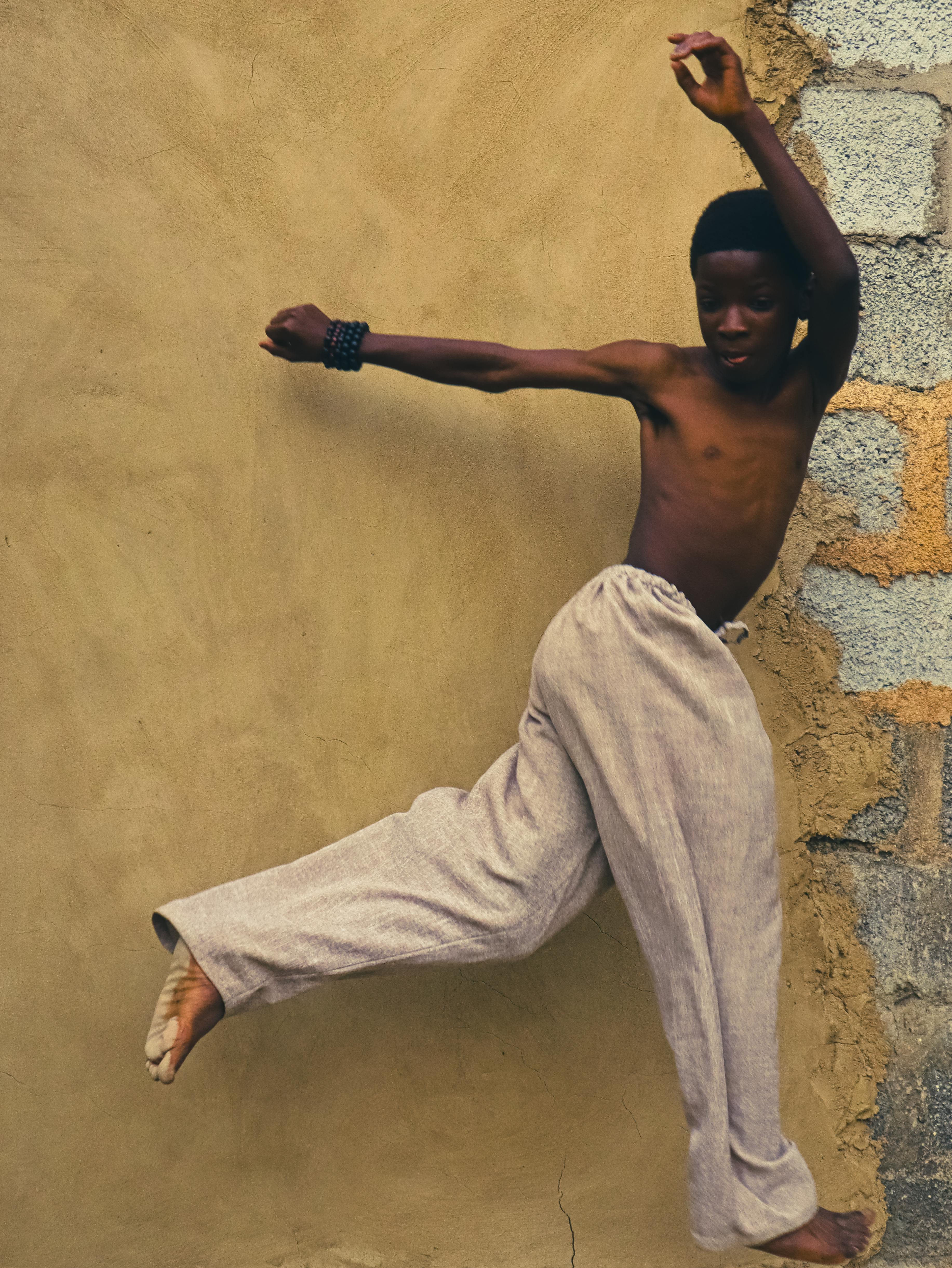 Shirtless Boy Dancing Against Wall