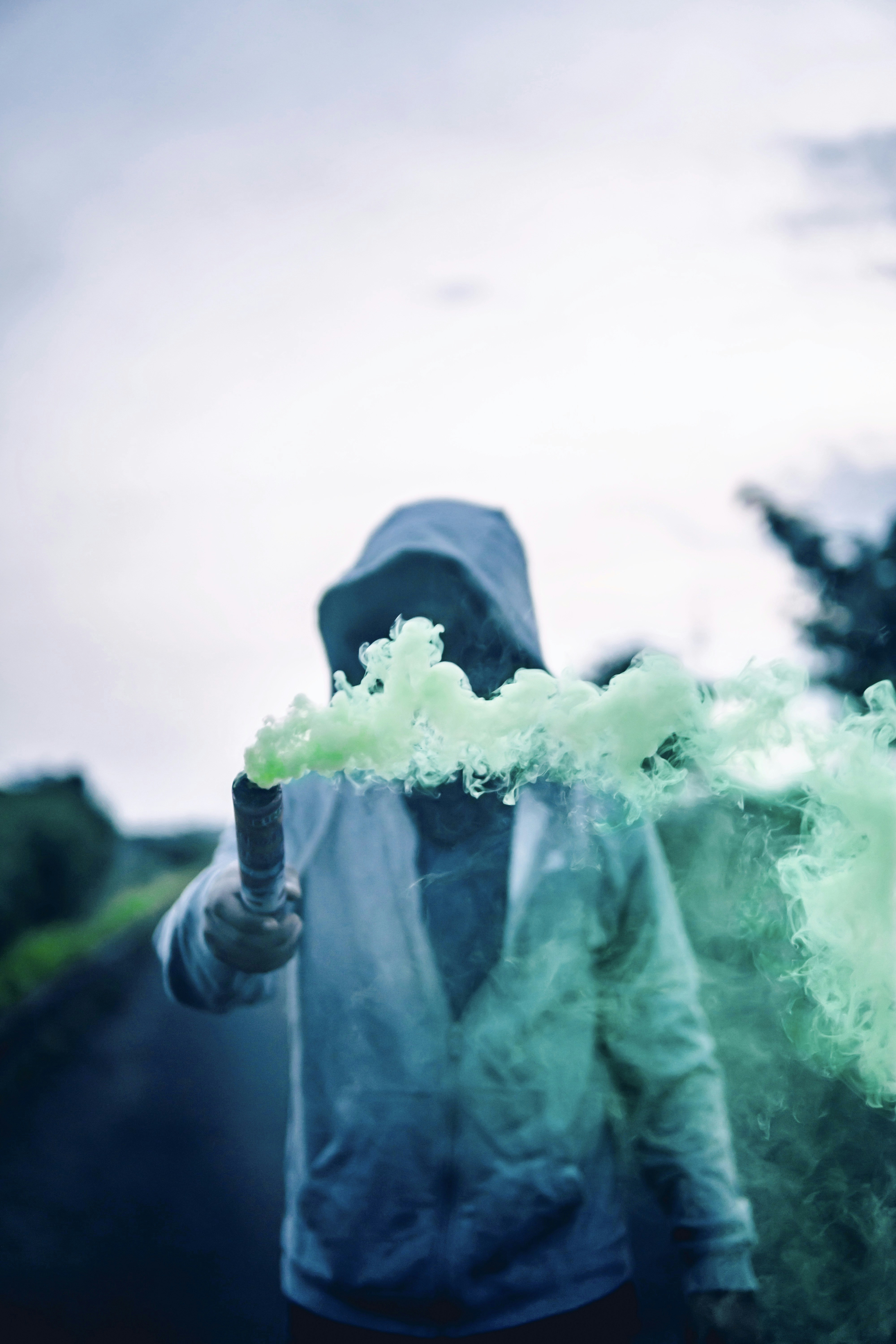 Hooded Person Holding Green Smoke Flare