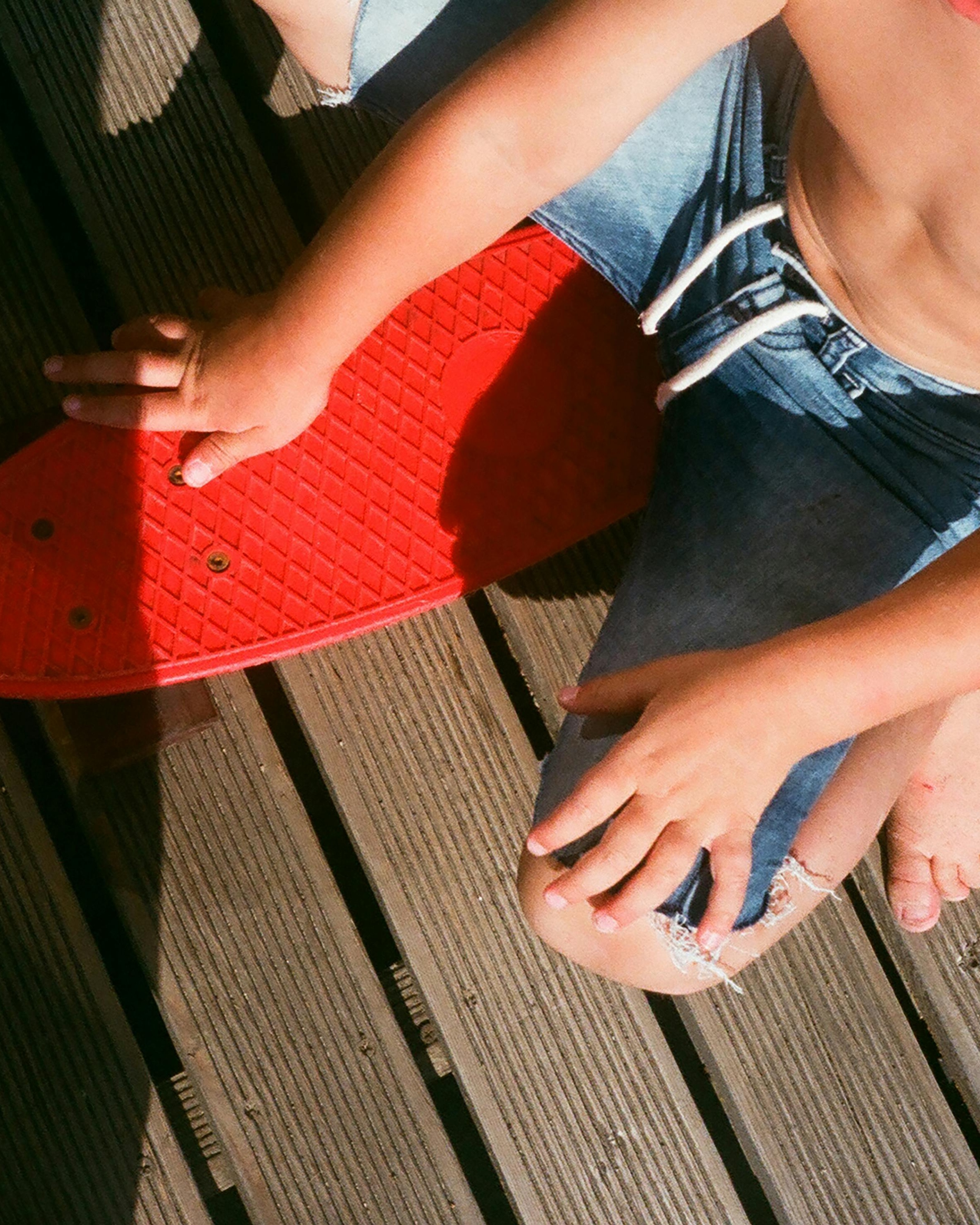 Child Sitting With Red Skateboard