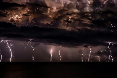 Multiple Lightning Strikes Over Dark Ocean