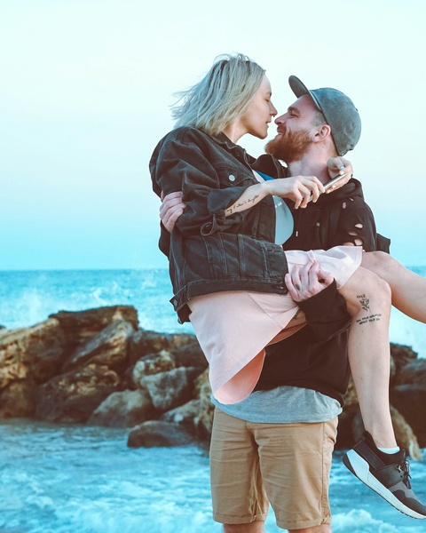 Couple Embracing By Rocky Seaside