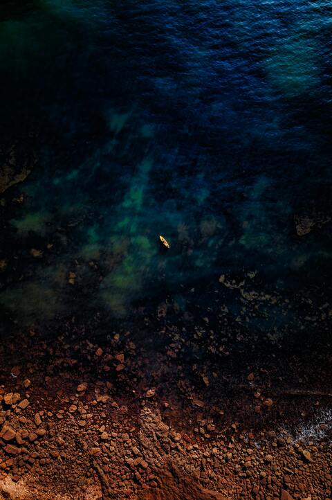 Aerial View of Lone Kayak on Coastal Sea