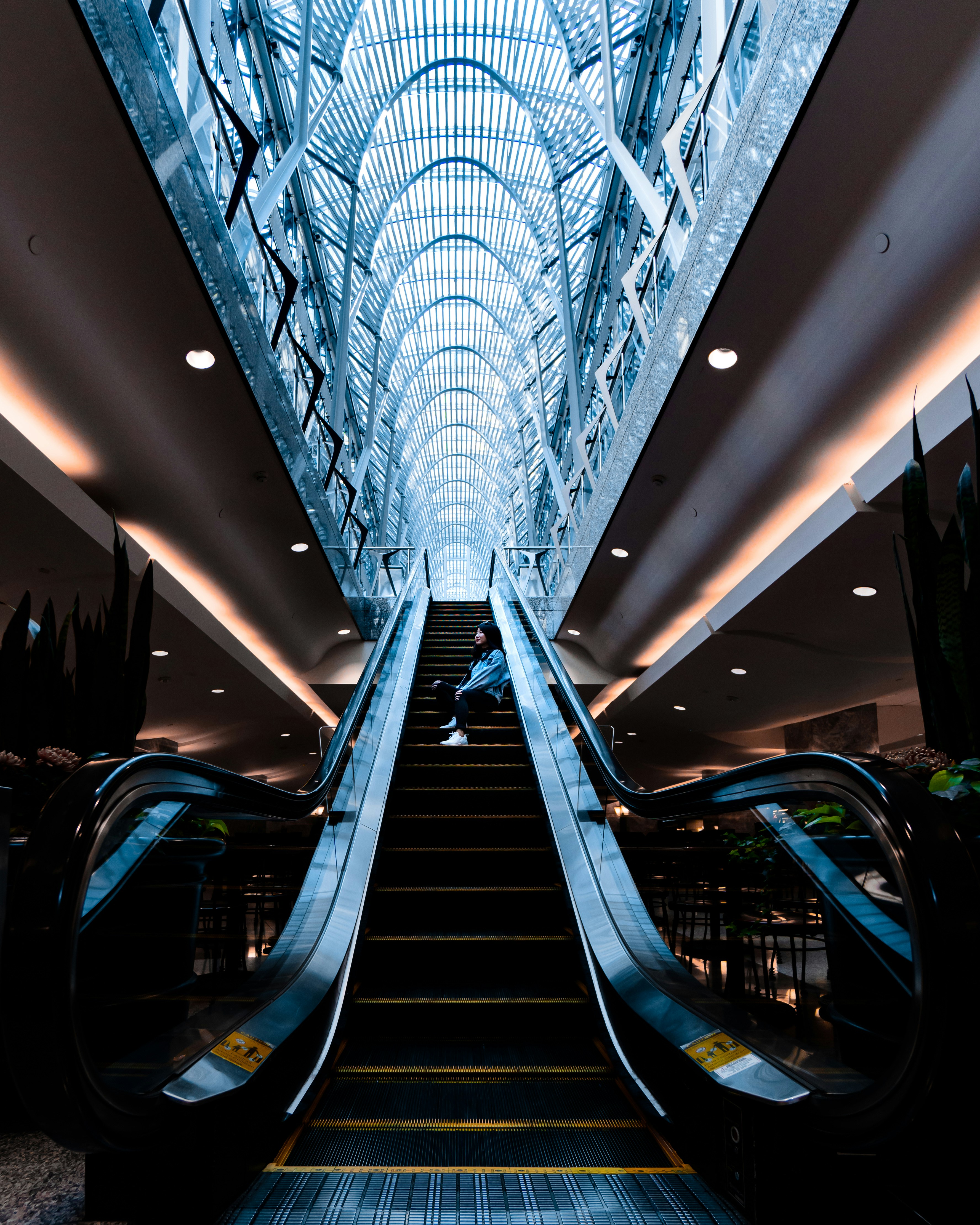 Woman Sitting on Escalator in Atrium