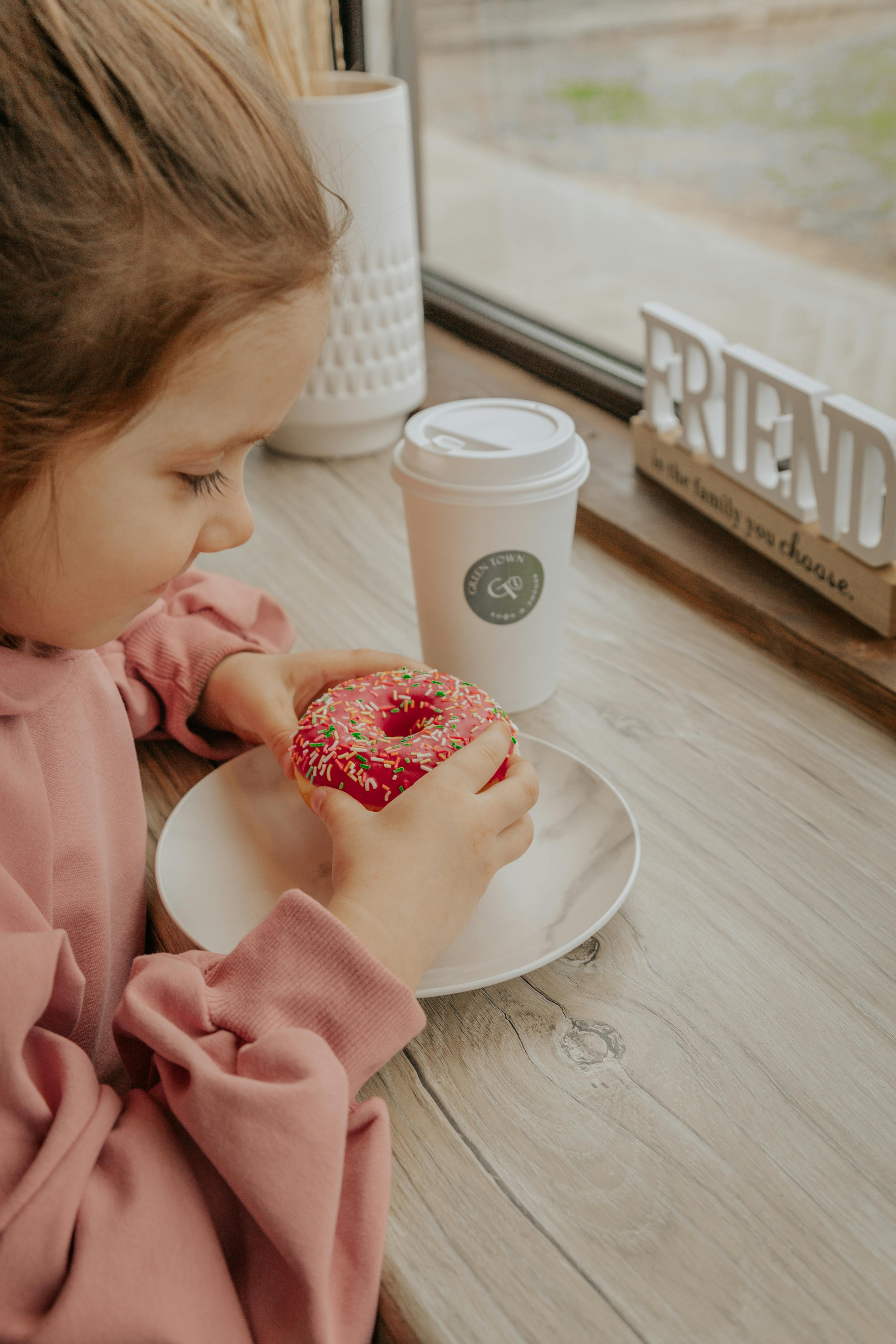 Little Girl With Donut At Window Table