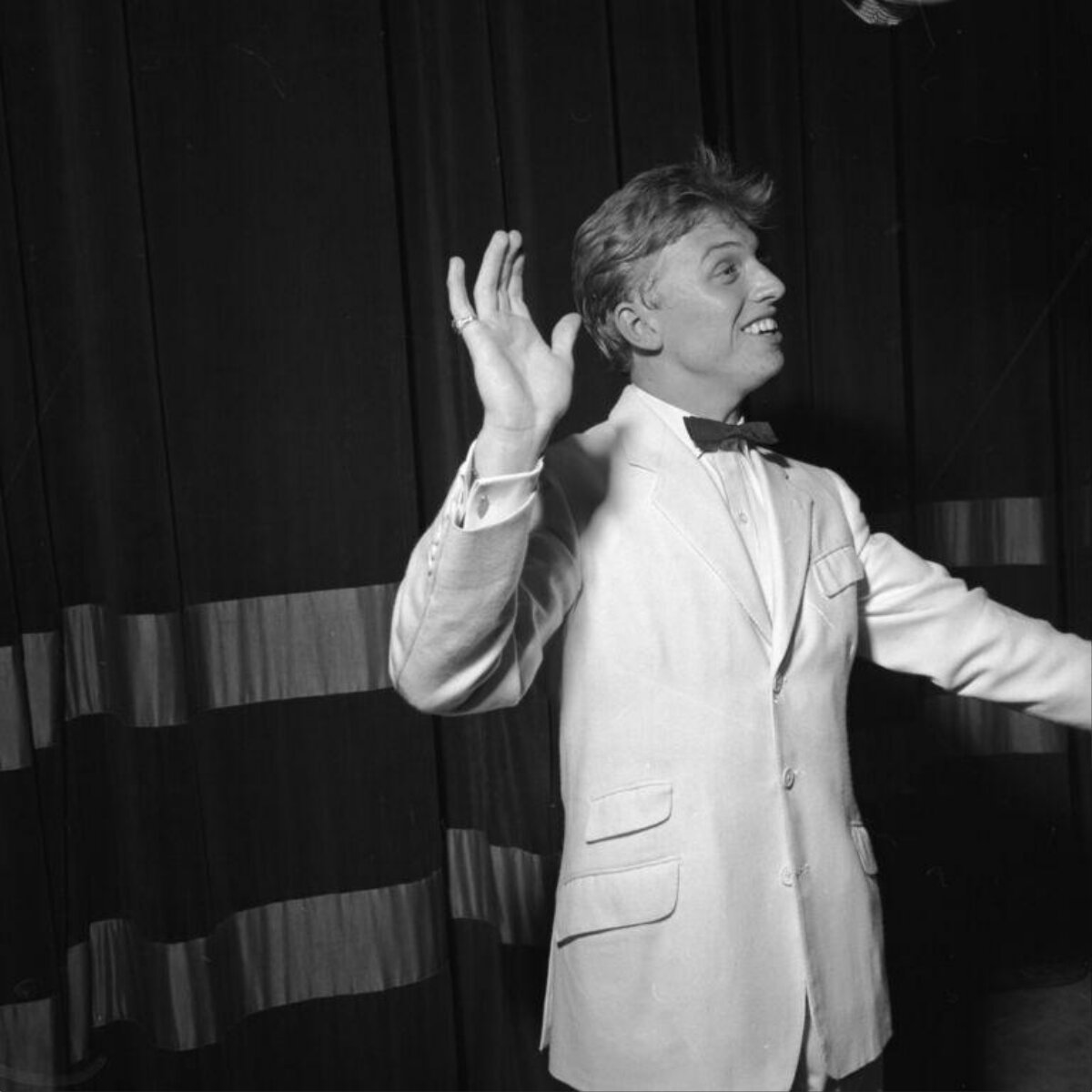 Smiling Male Performer Waving on Stage