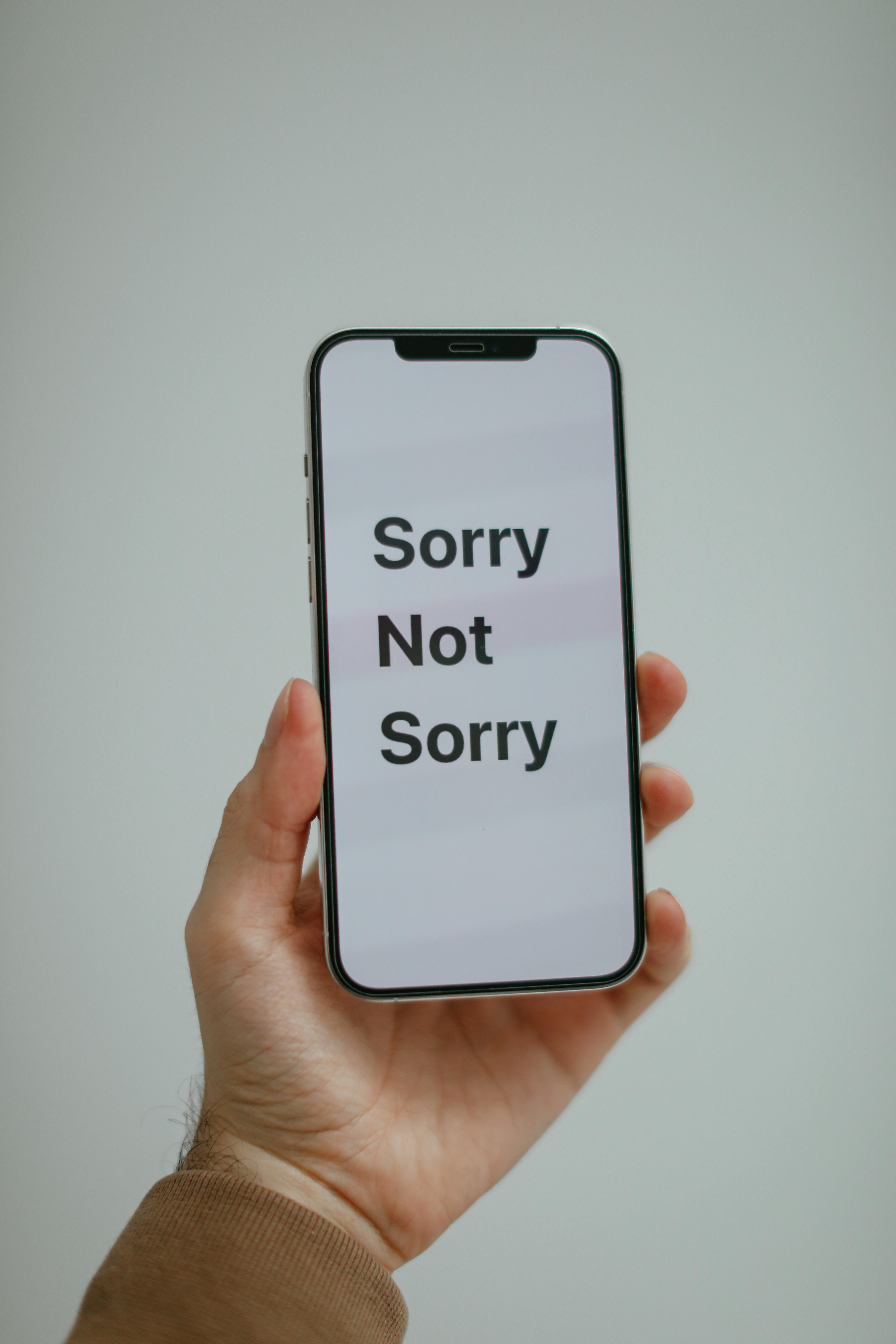 Hand Holding Phone With Sorry Not Sorry Text